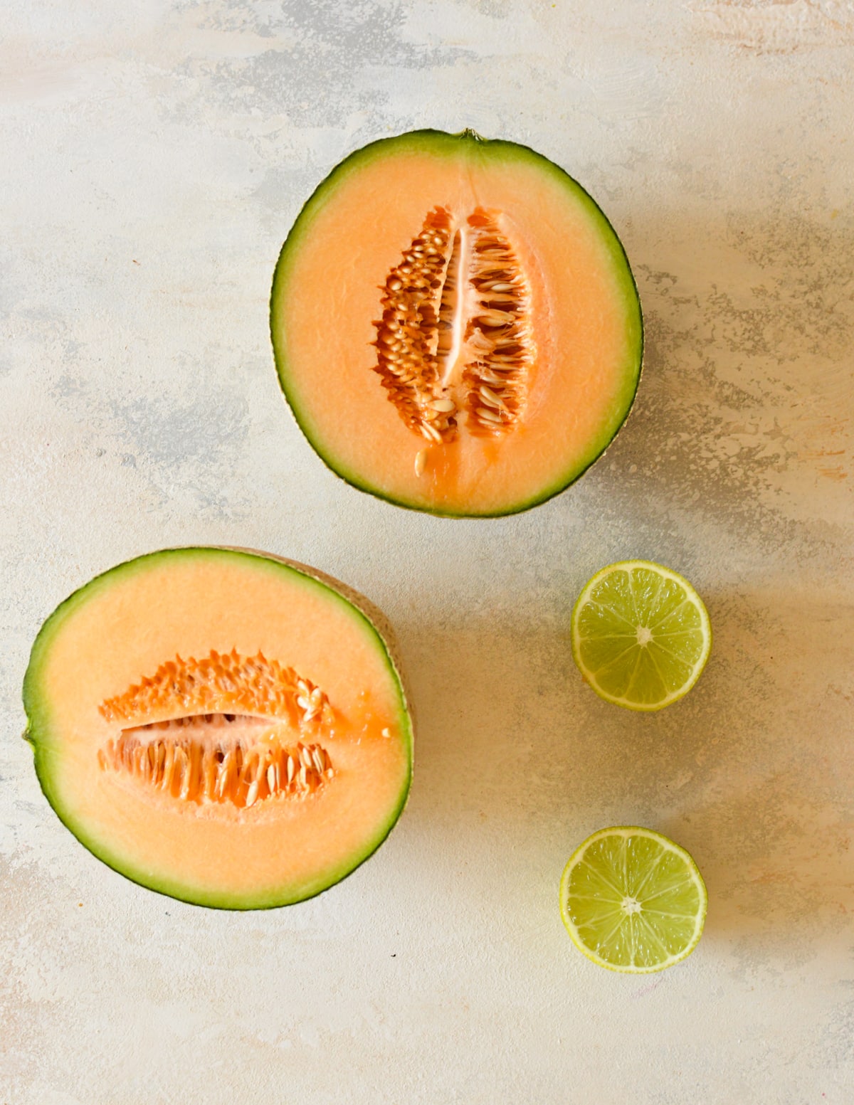 a cantaloupe cut in half and a lime.