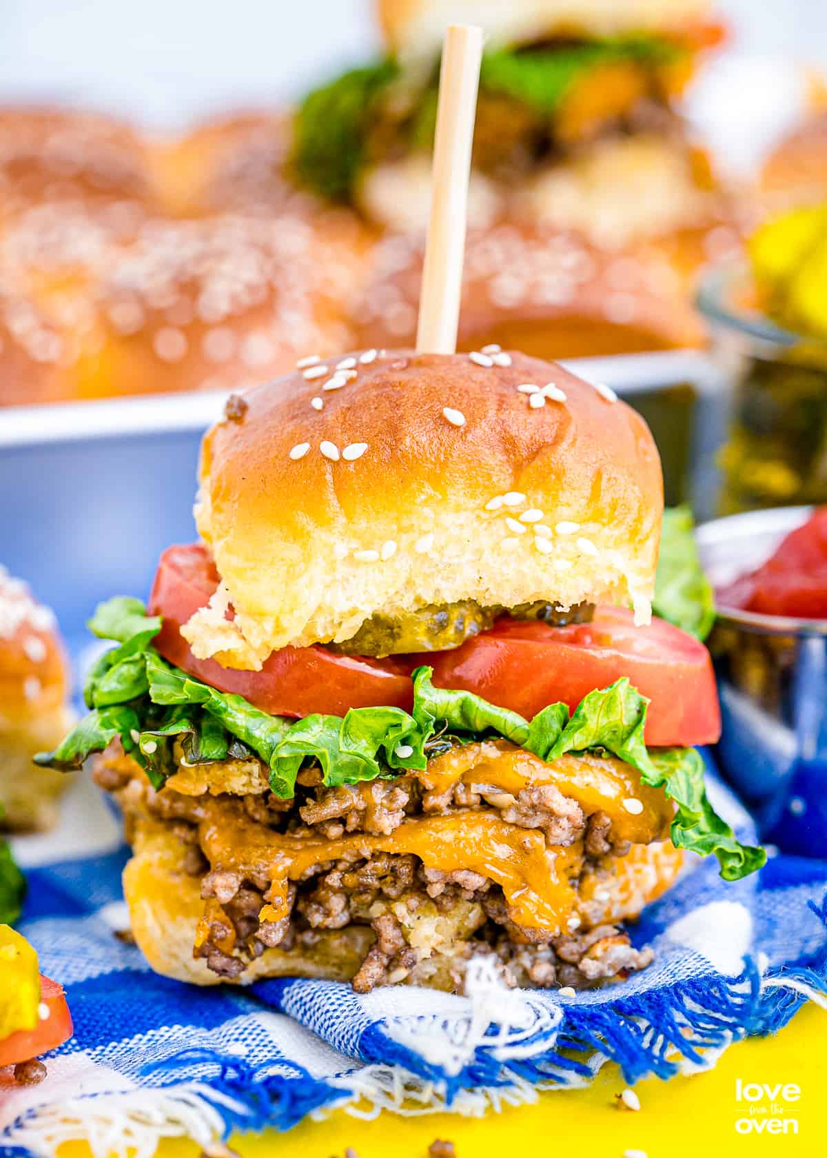 a cheeseburger slider with lettuce and tomato.