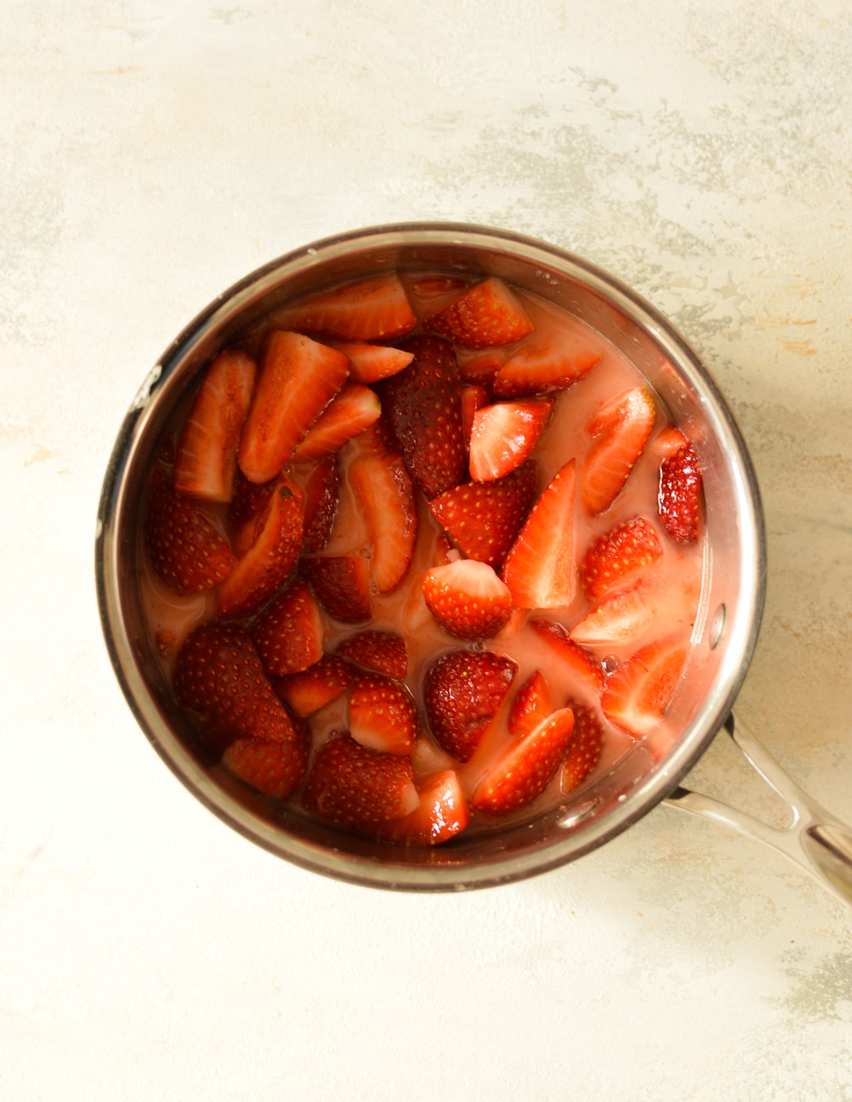 Quartered fresh strawberries, sugar, and lemon juice added to a saucepan with cornstarch slurry, ready for cooking into a delicious filling.