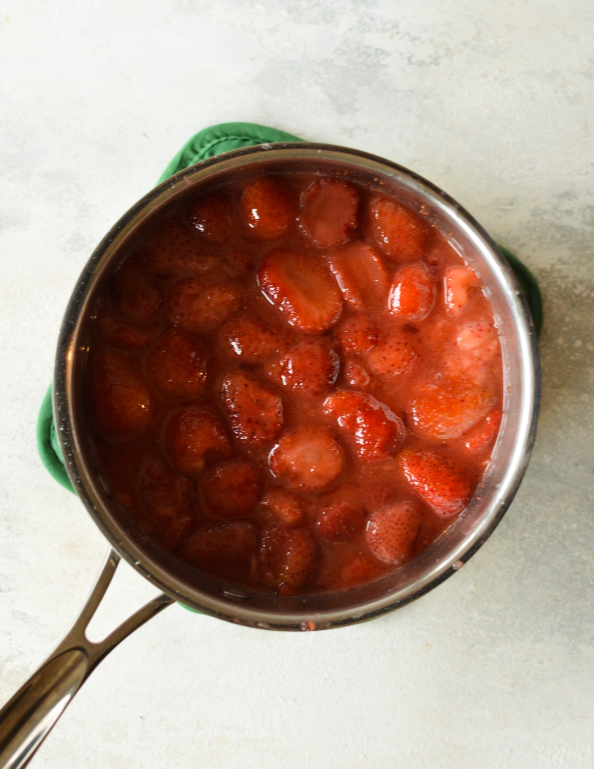 Strawberries simmering in a saucepan, beginning to break down and release their juices, creating a delicious syrup for the filling.