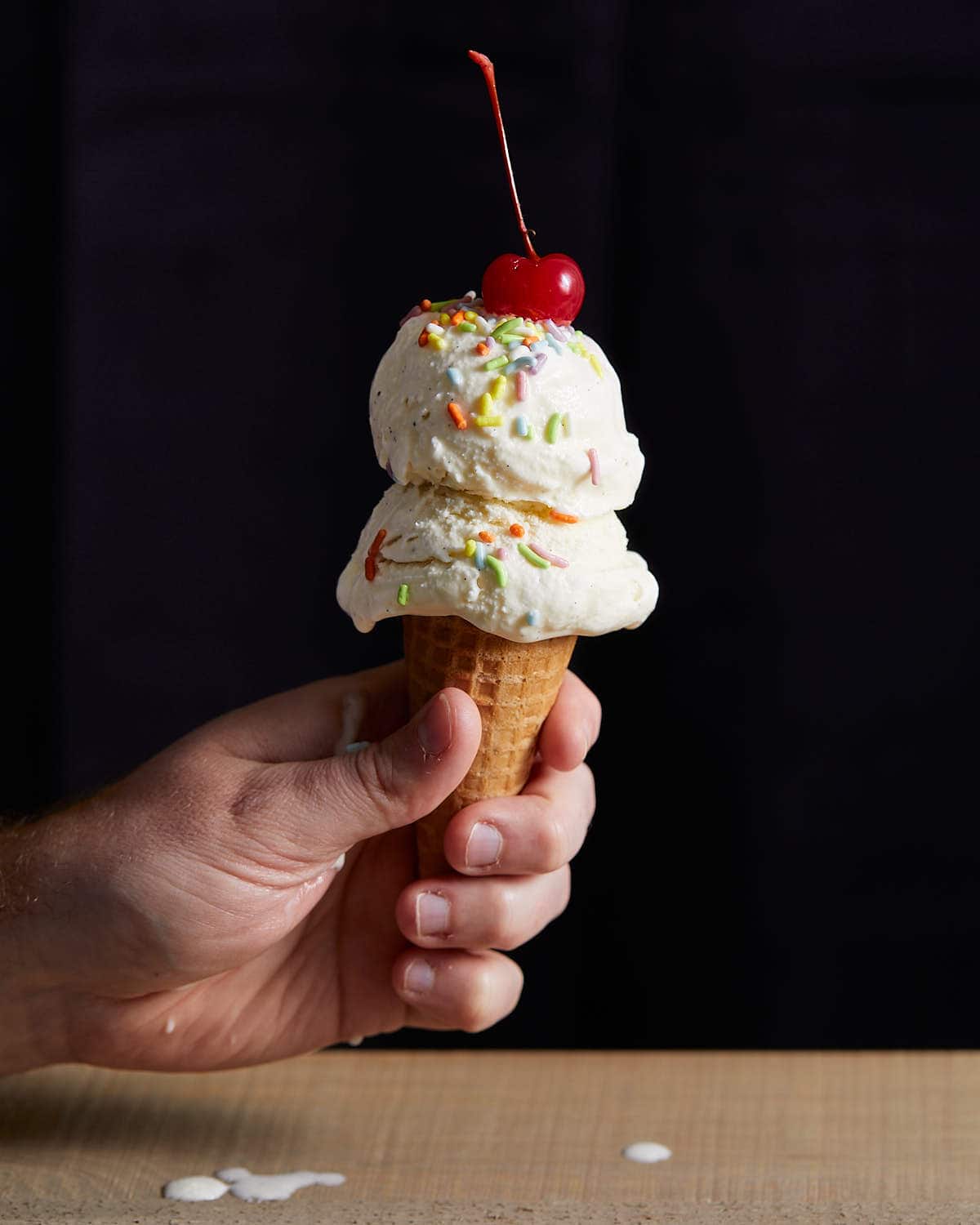 vanilla ice cream with a cherry on a cone.