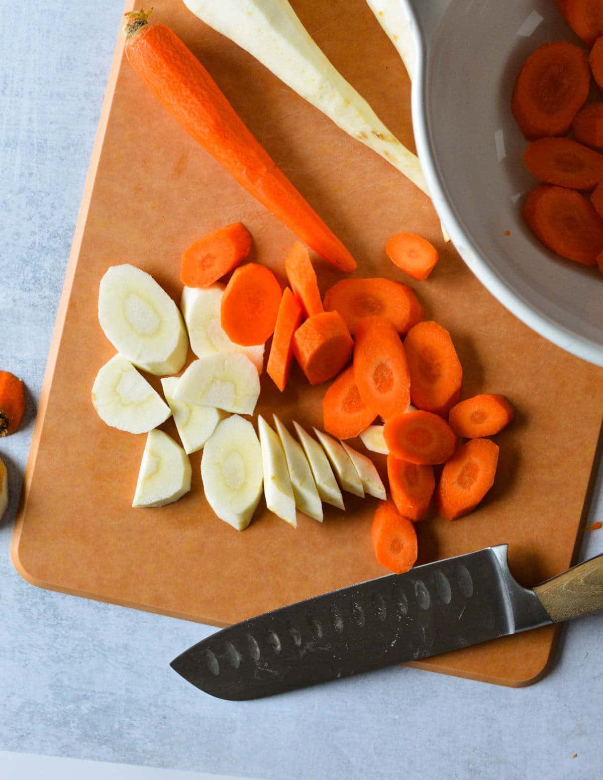 sliced carrots and parsnips on a cutting board.
