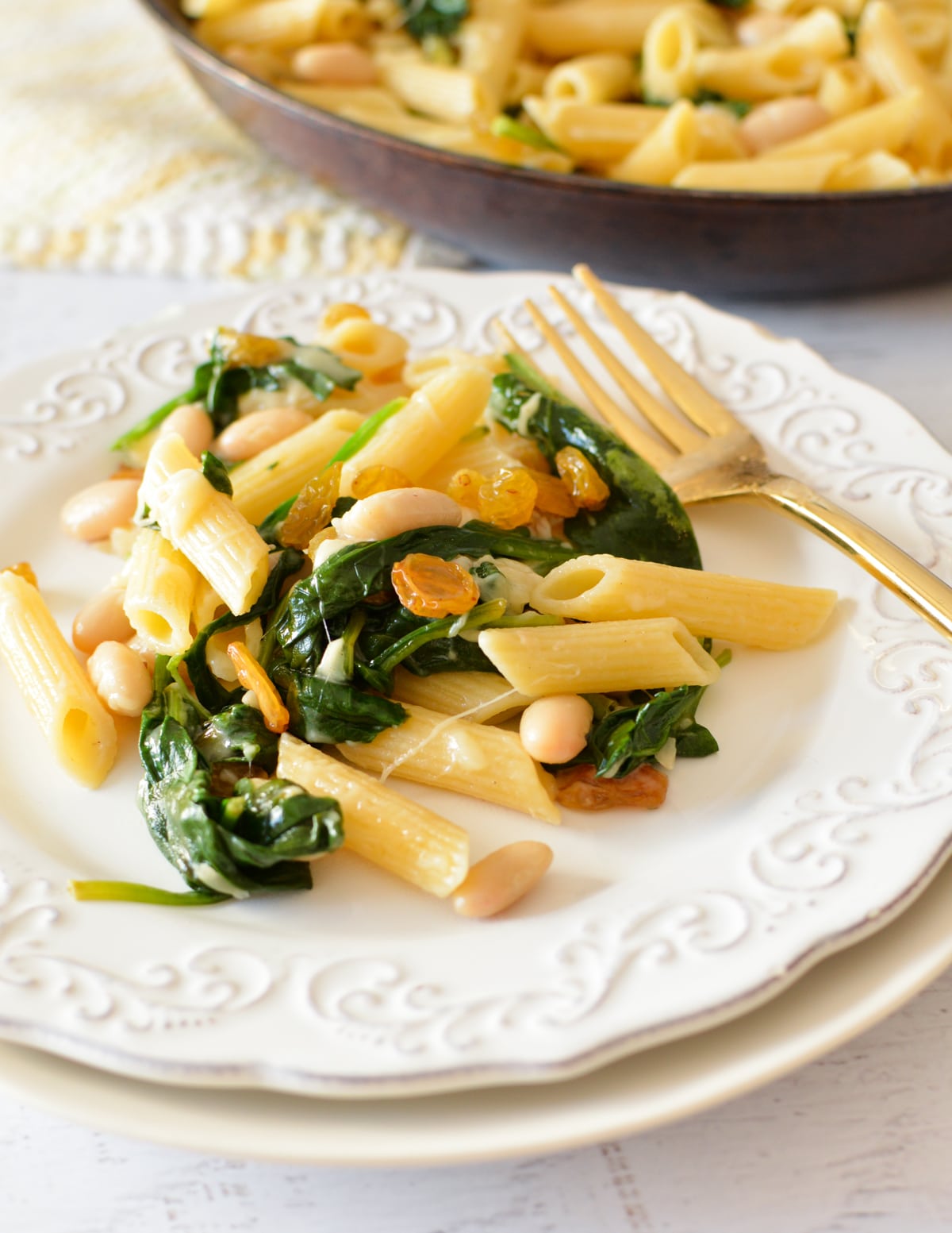 a plate of spinach pasta with raisins and parmesan.