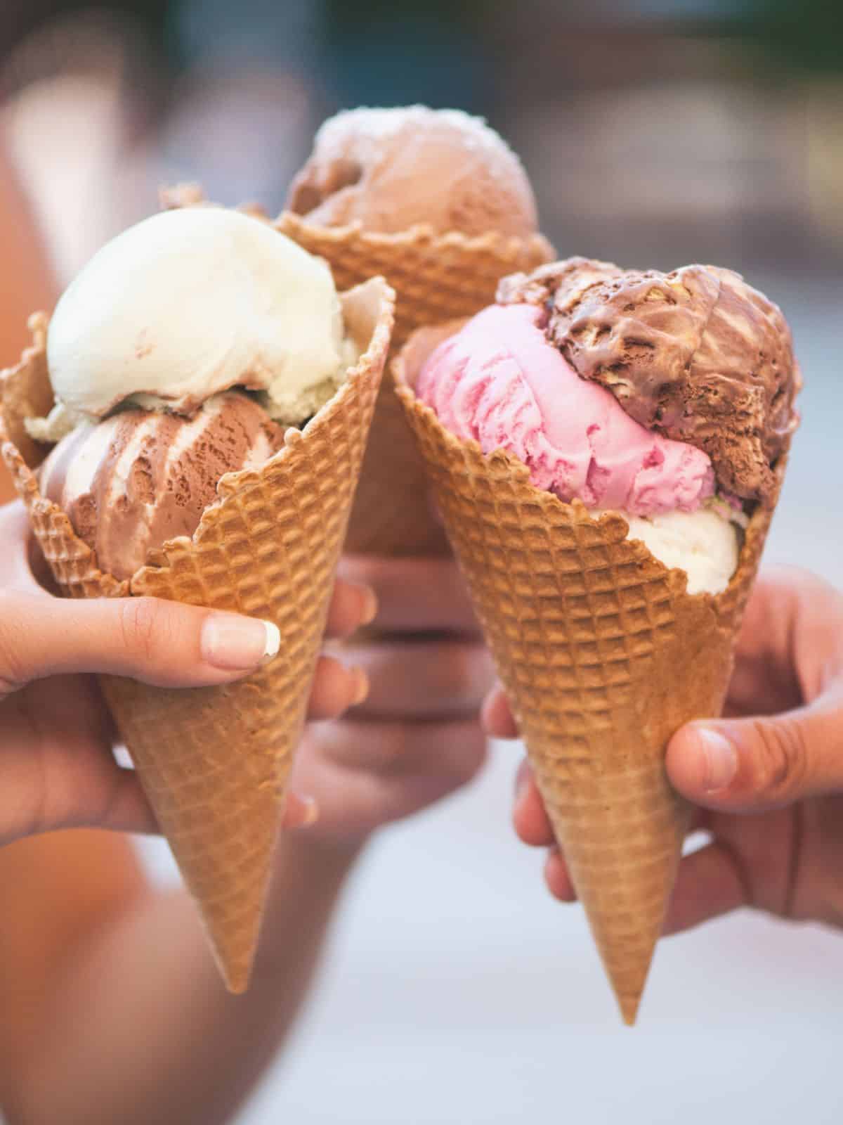three waffles cones with triple scoops of ice cream.