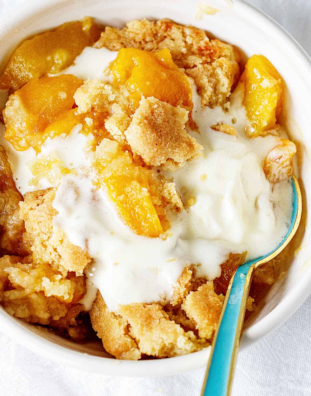 peach dump cake with ice cream in bowl.