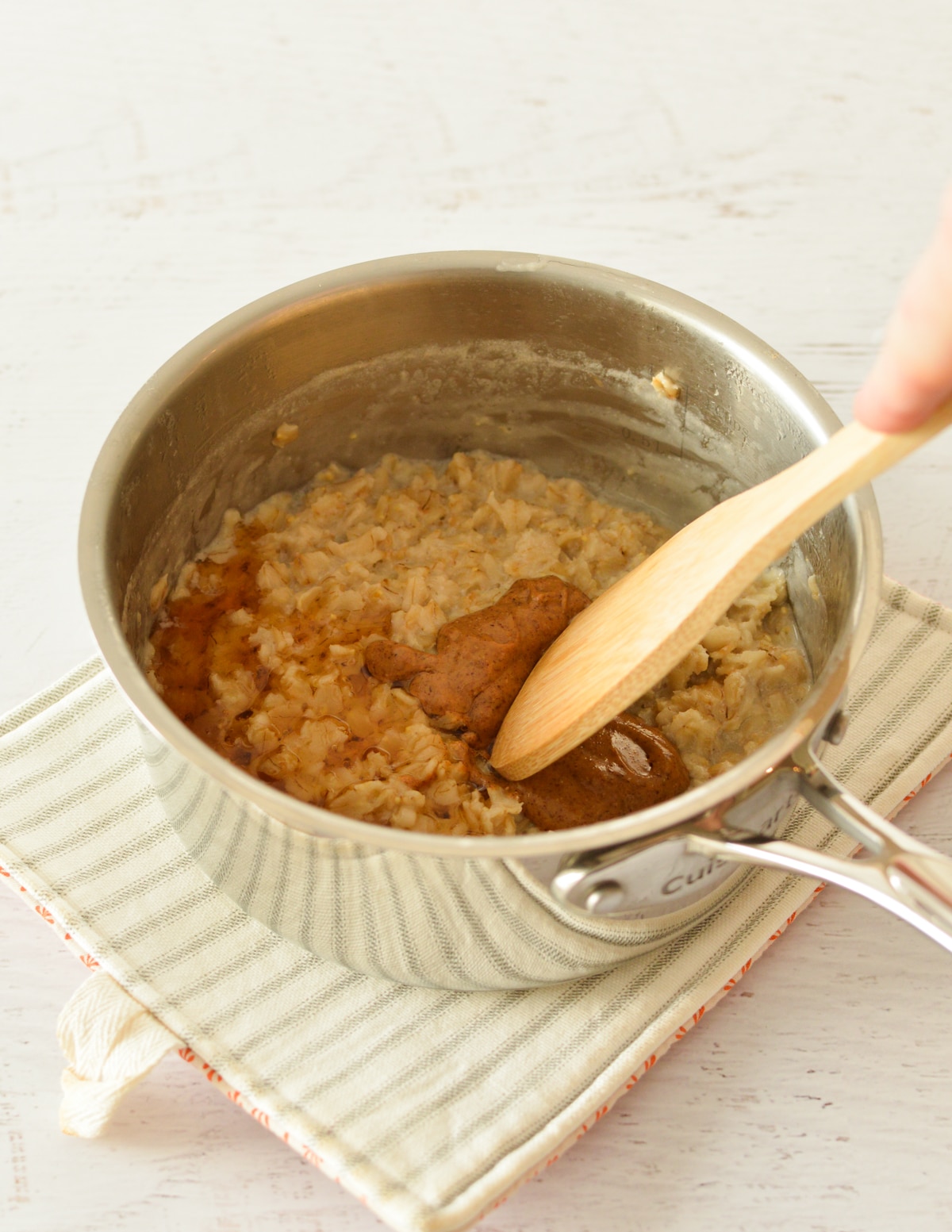 a saucepan of oatmeal with almond butter and maple syrup.