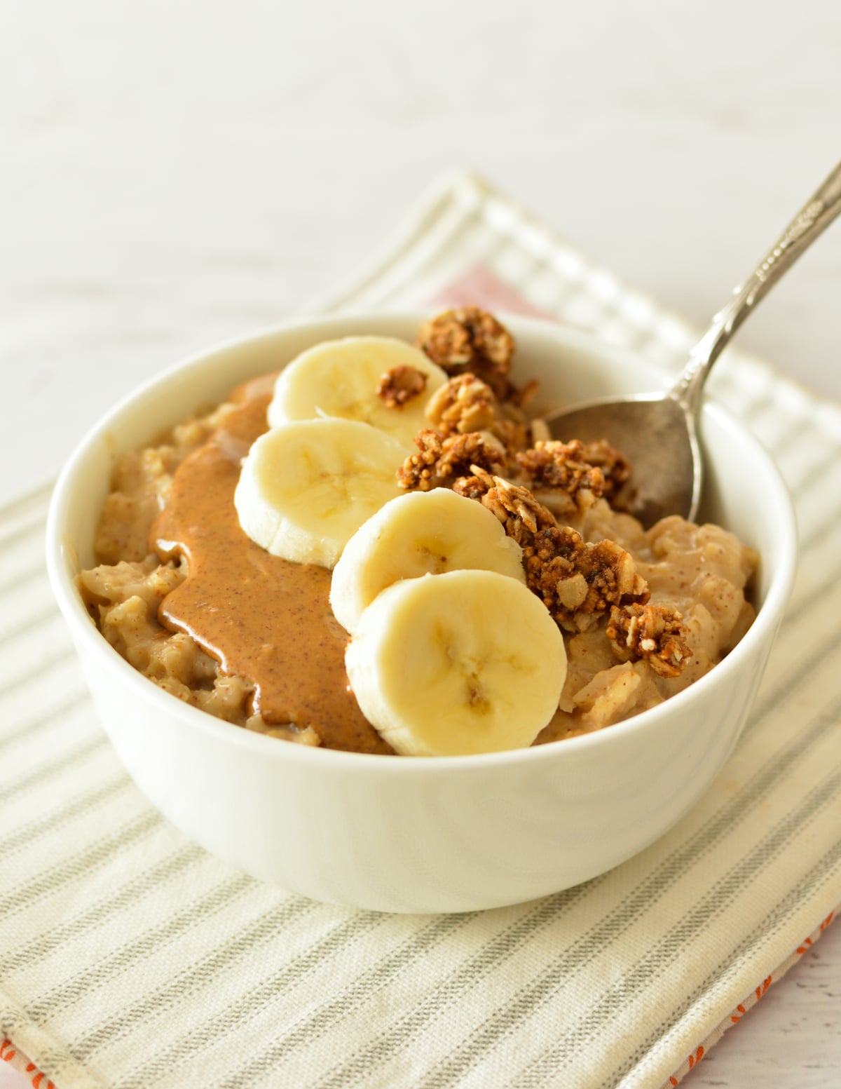 a bowl of oatmeal with bananas and almond butter on top.