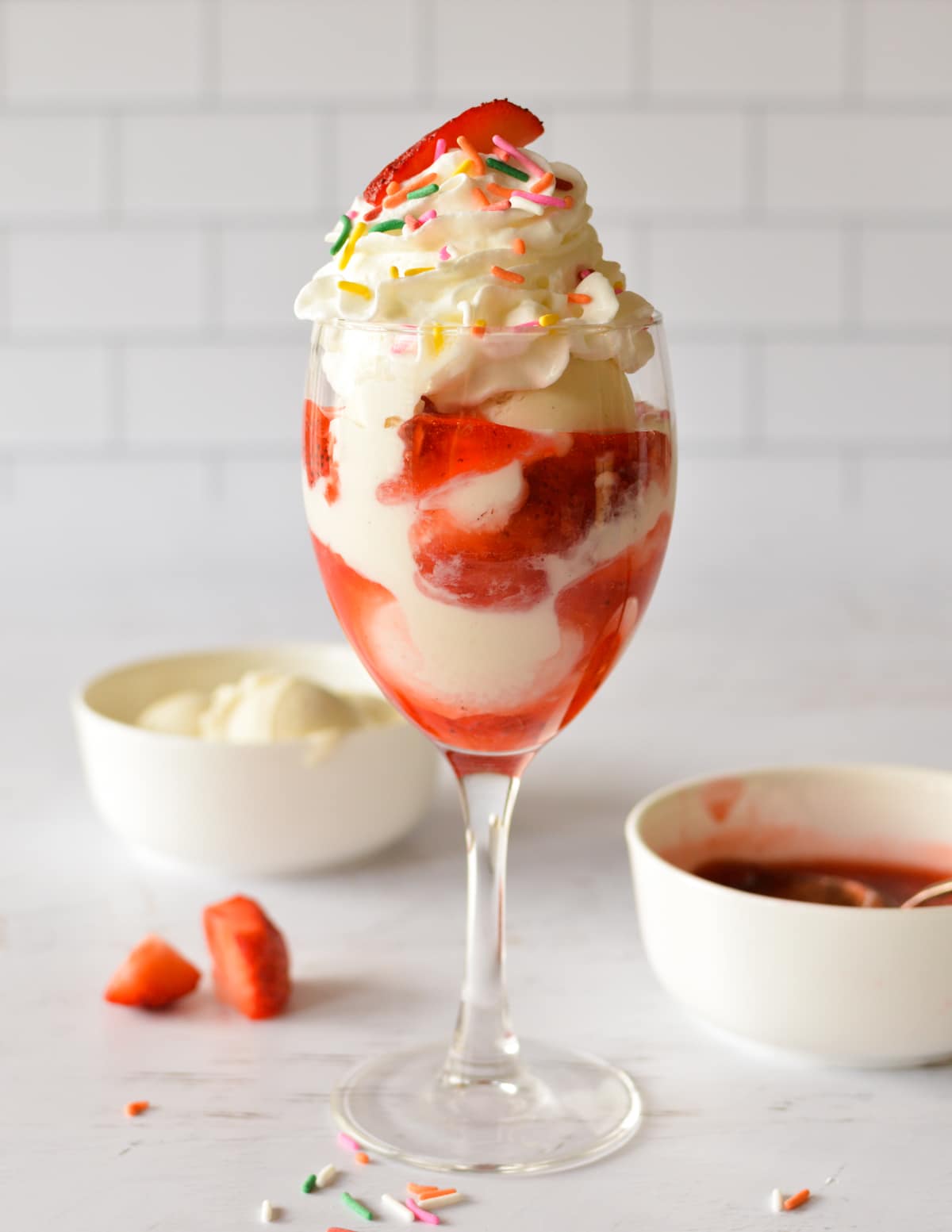 a strawberry sundae with whipped cream and sprinkles.