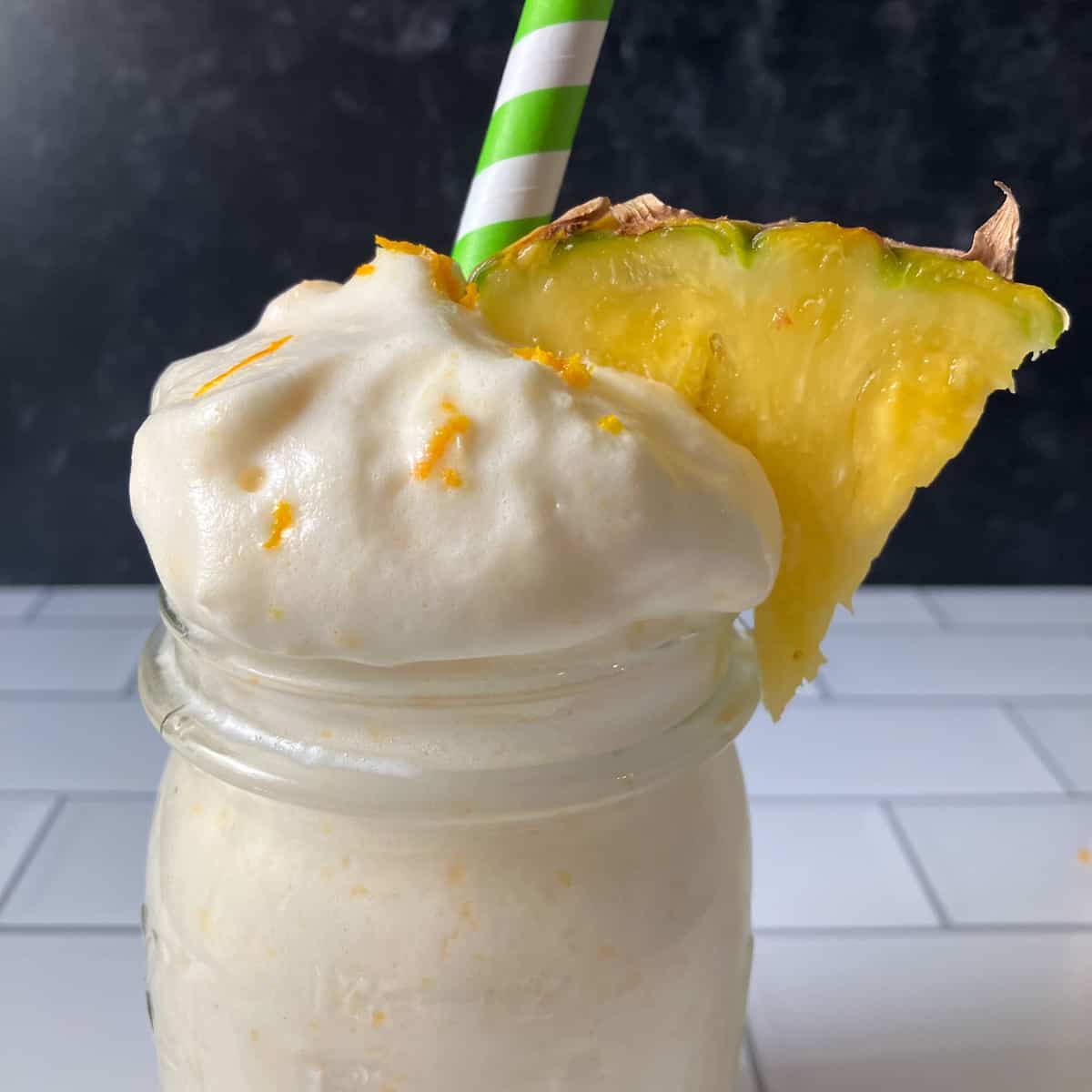 a peach pineapple smoothie with whipped cream and pineapple.