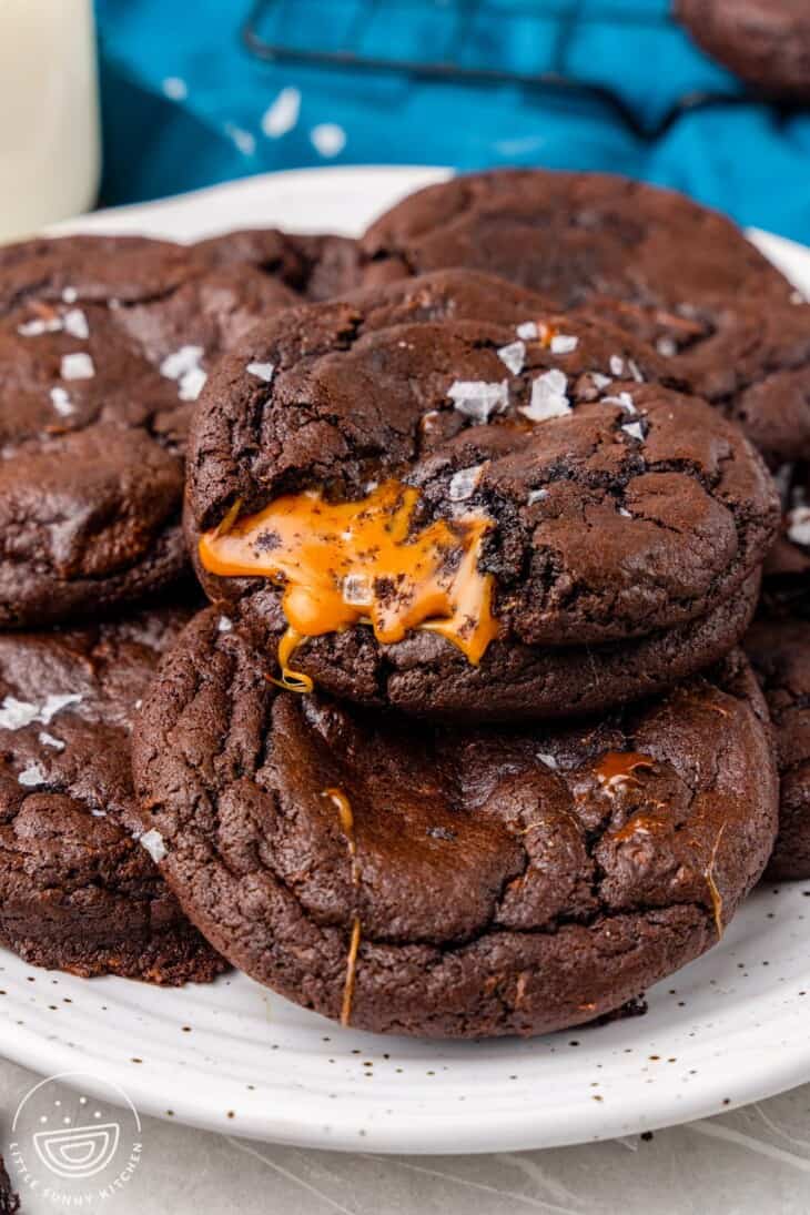 a plate of chocolate caramel cookies with a bite out of one. 