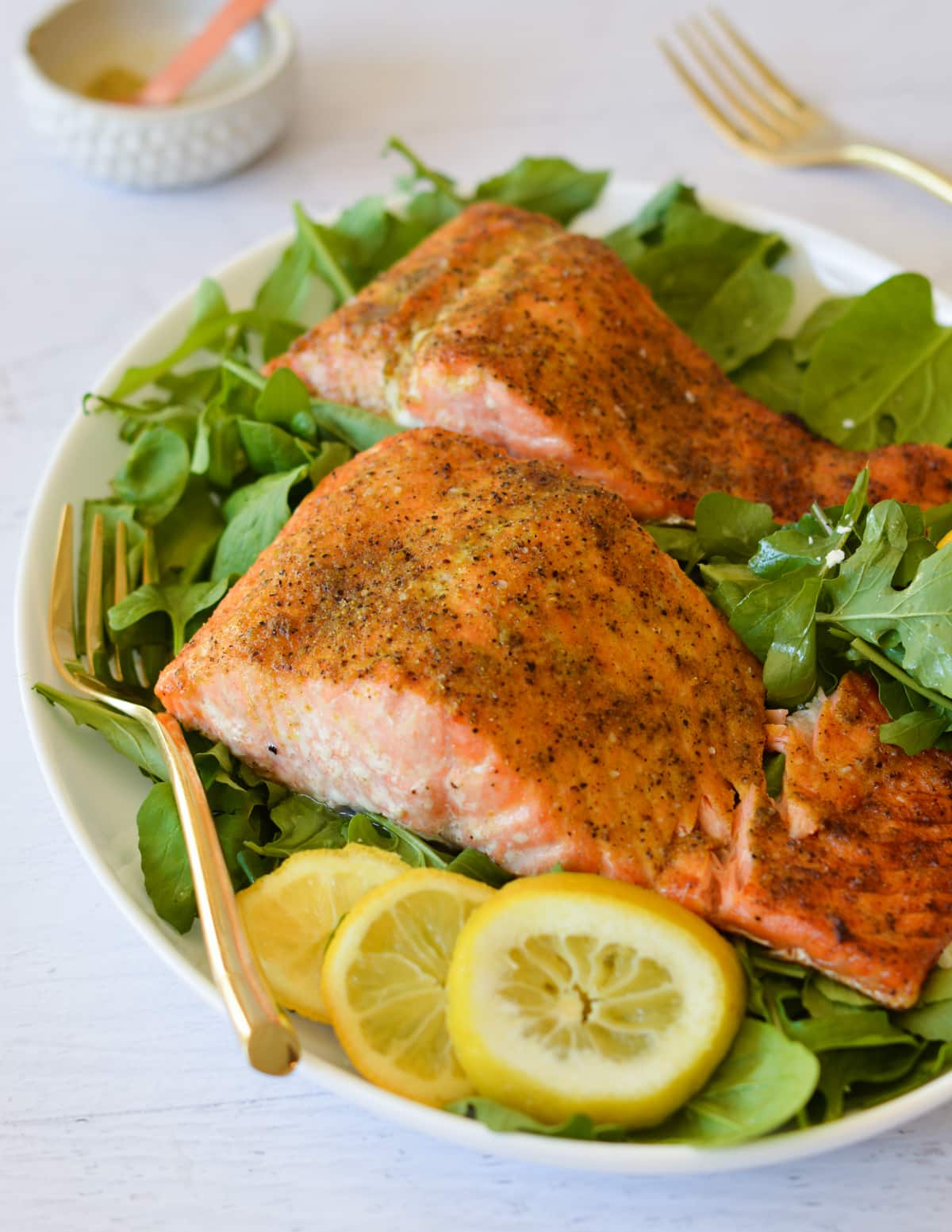 lemon pepper salmon on a bed of mixed greens.