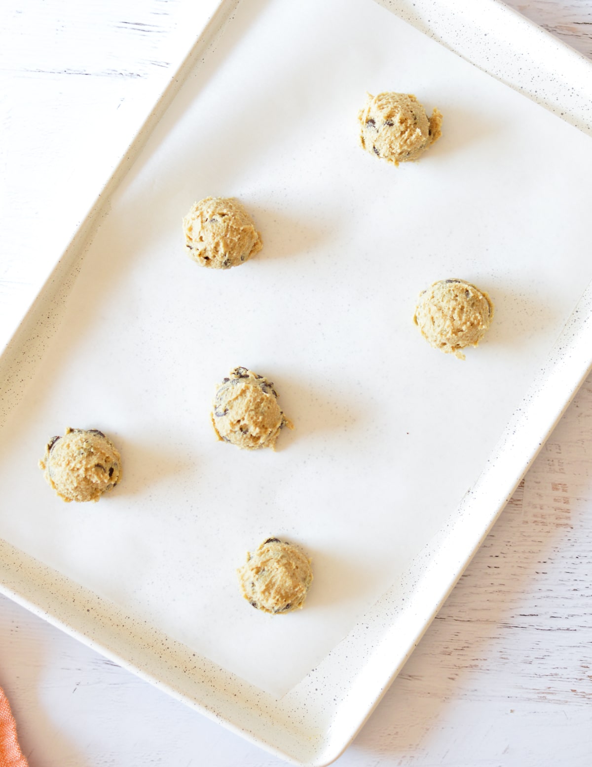 chocolate chip cookie dough balls on a sheet pan. 