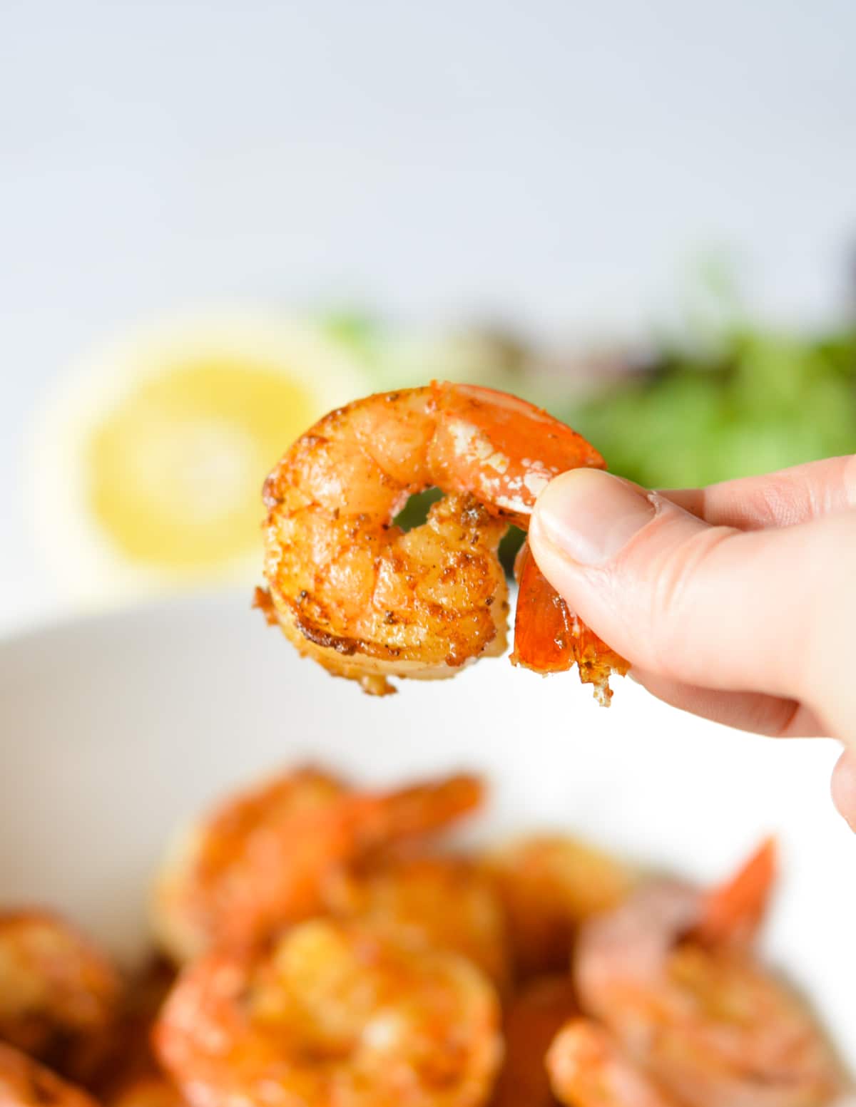 hand holding a cooked shrimp. 