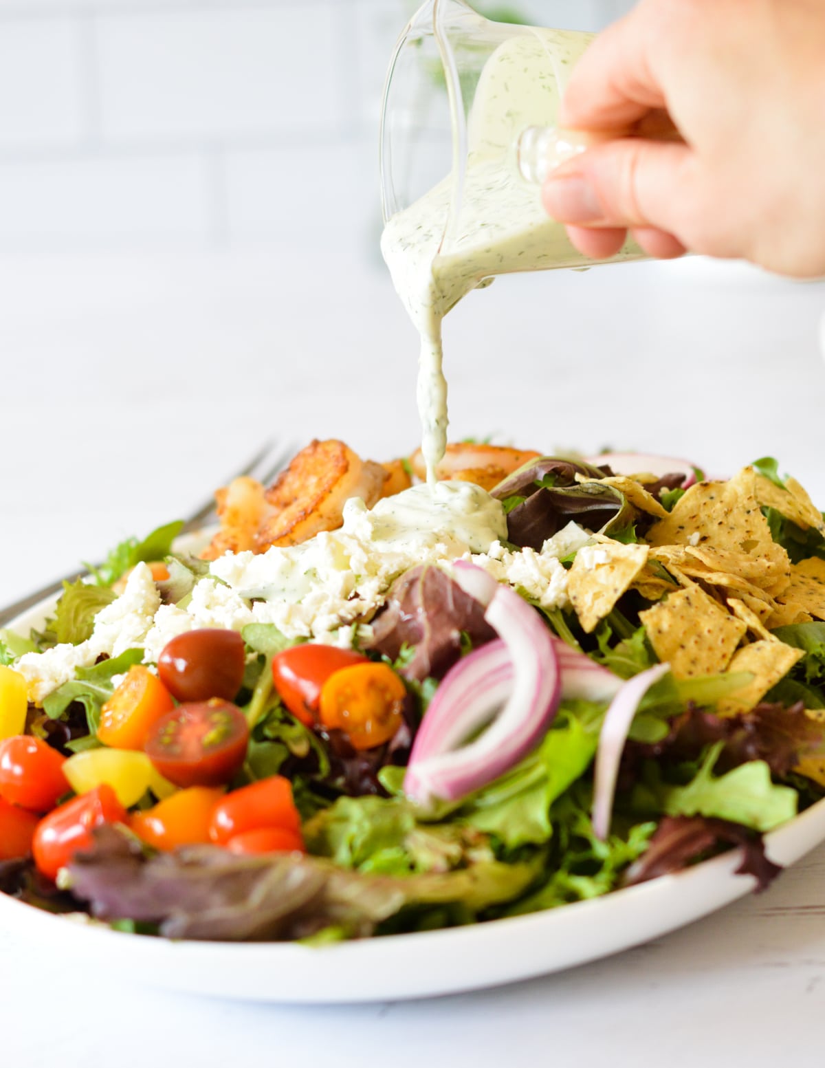 drizzling creamy dressing on a salad.