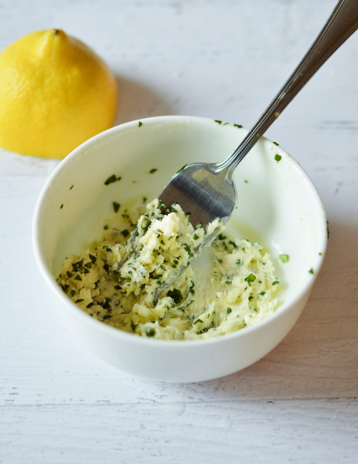 a bowl of lemon basil butter with a fork in it.