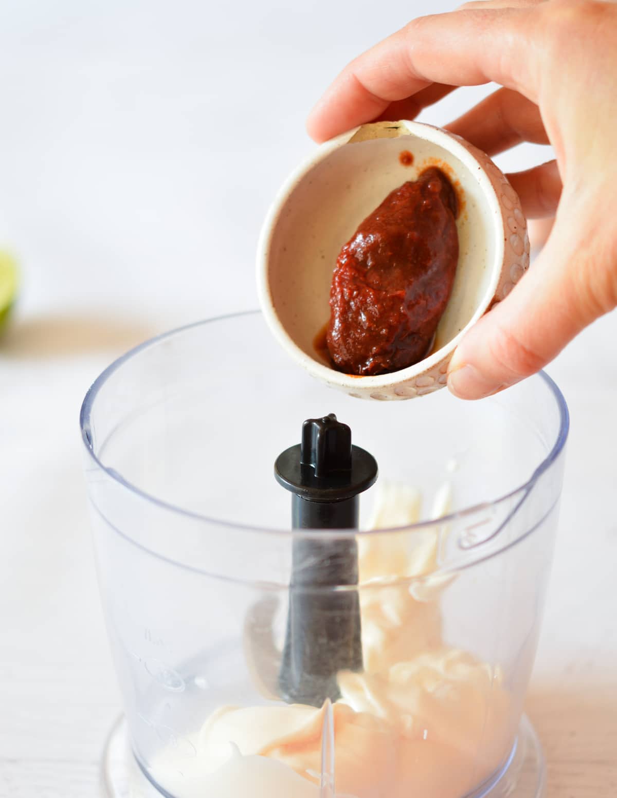 adding a chipotle to a food processor with mayo.