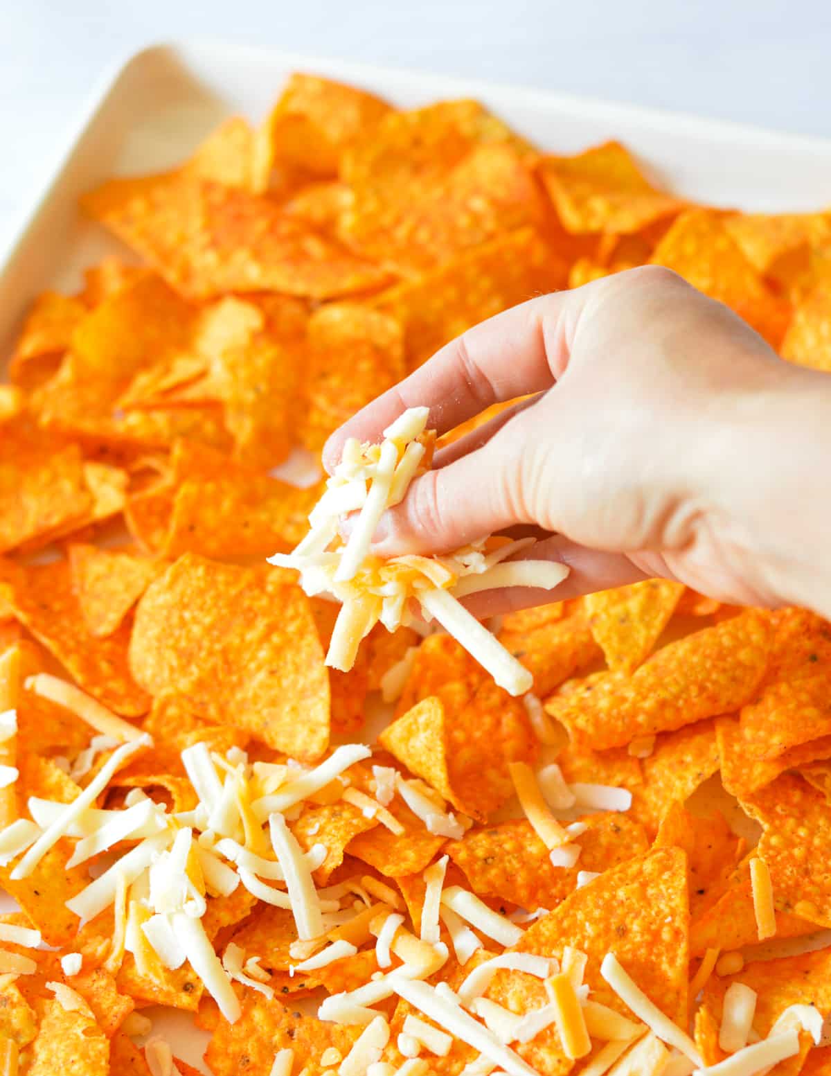 hand sprinkling cheese on doritos.