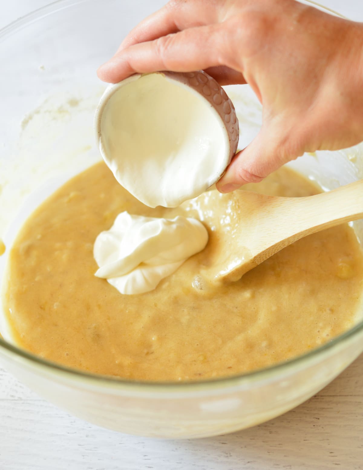 pouring sour cream into banana bread batter.