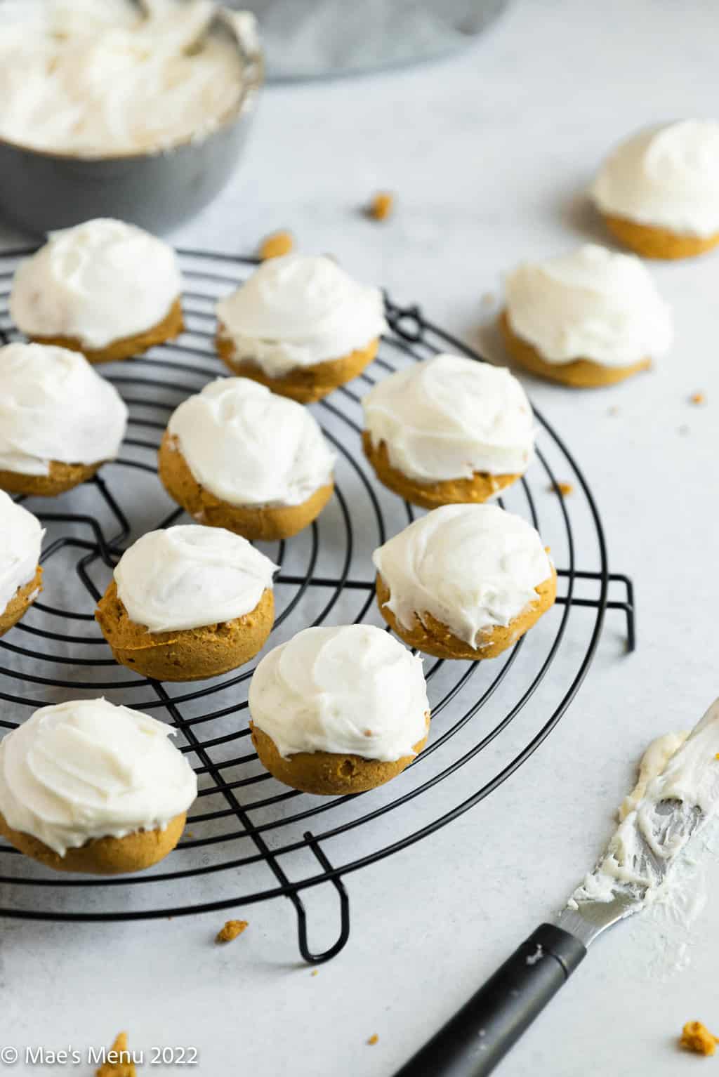 gluten free pumpkin cookies with icing on a wire rack.
