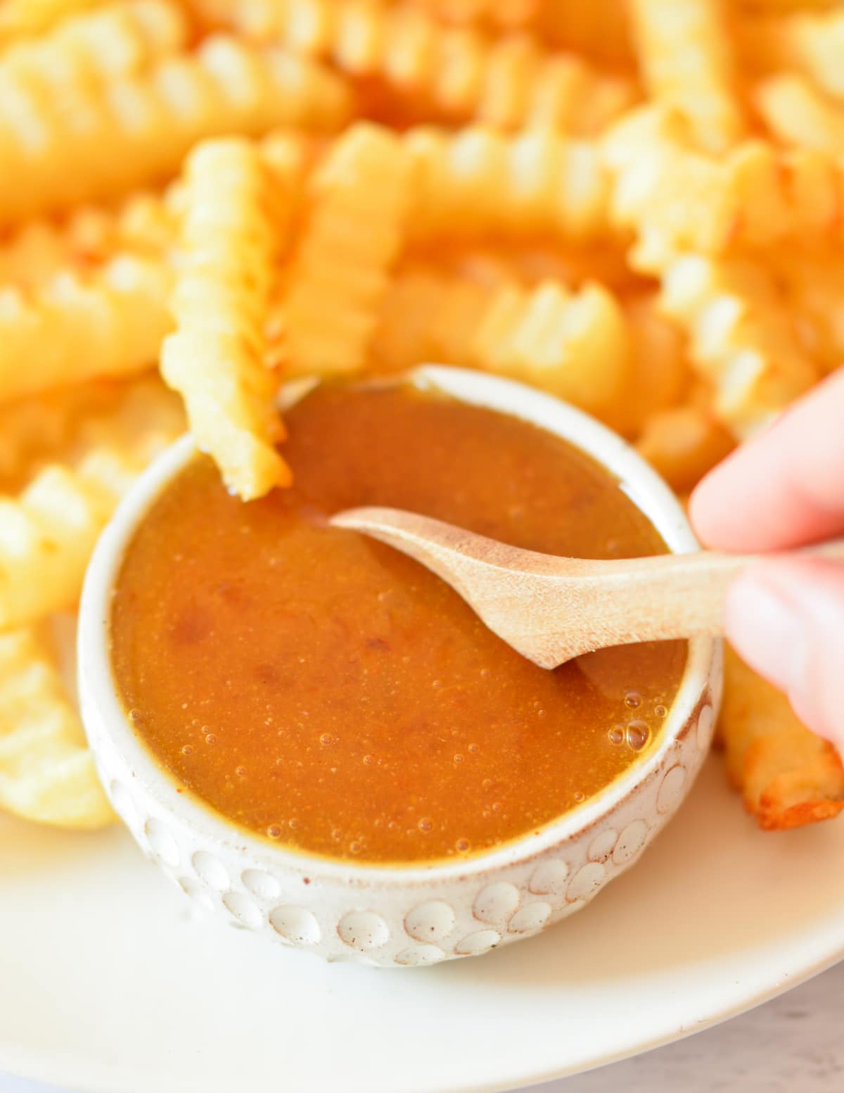 a bowl of sweet and sour sauce with fries.