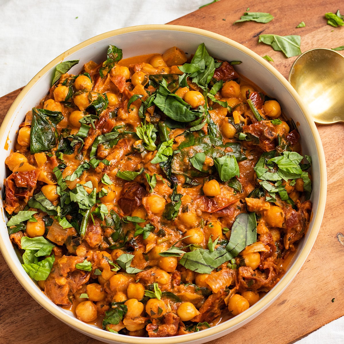 chickpeas in a sundried tomato sauce in a bowl with spinach.