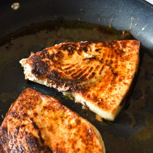 blackened swordfish in a skillet.