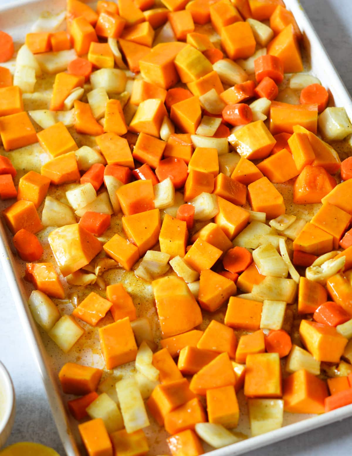 veggies coated in butter, oil, and brown sugar on a sheet pan.