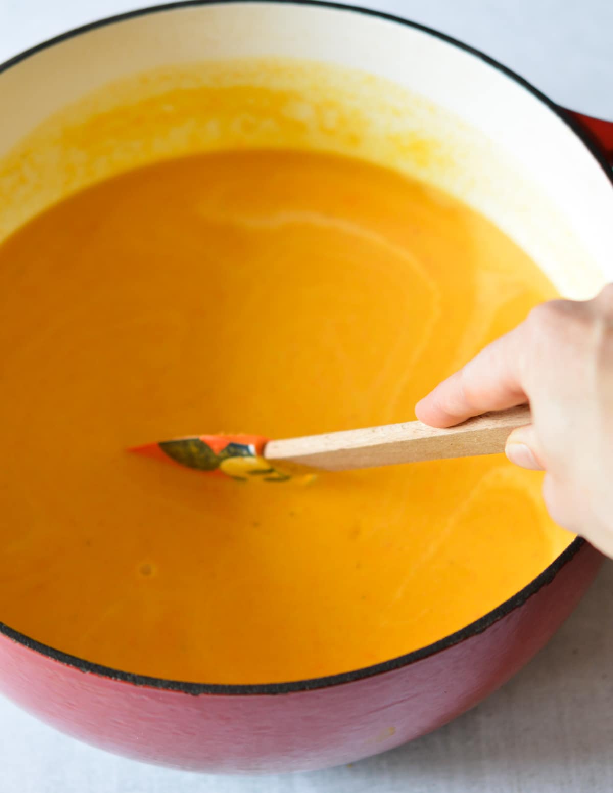 stirring butternut squash soup in a large dutch oven.