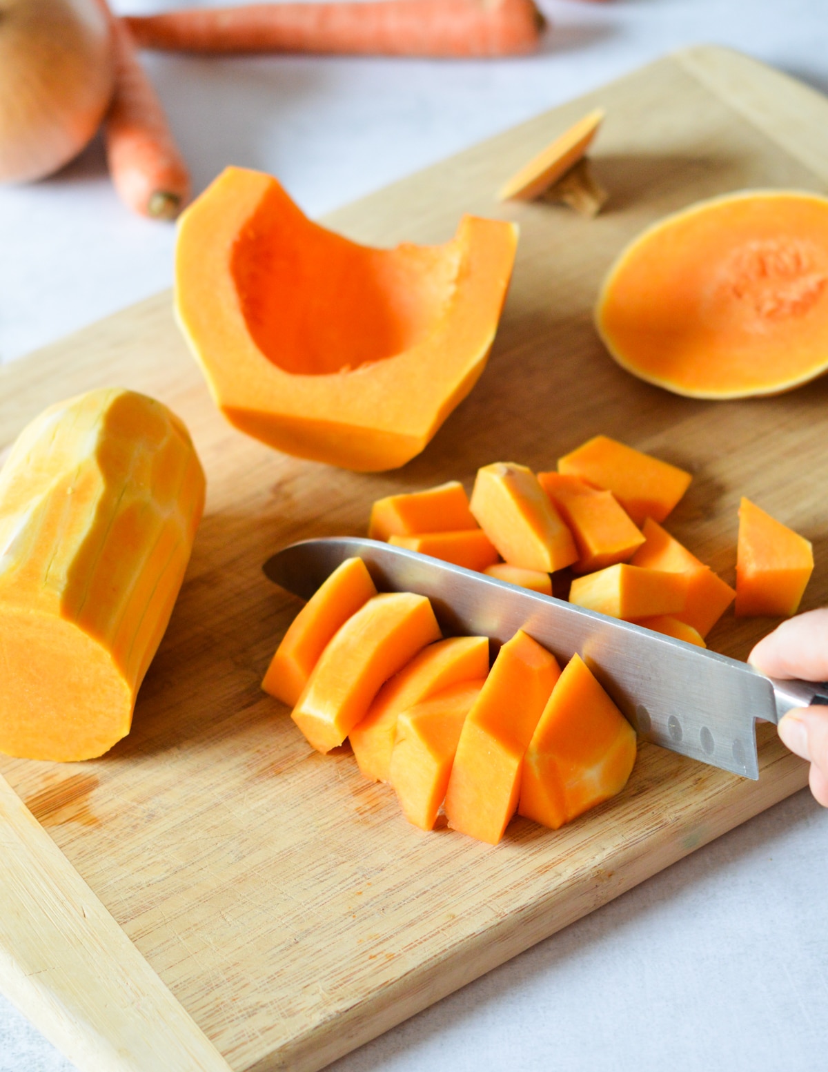 knife cutting butternut squash strips into chunks.