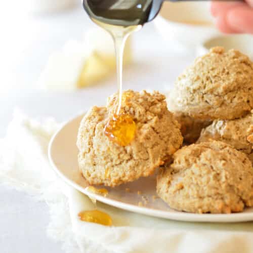 drizzling honey onto an oat flour biscuit.