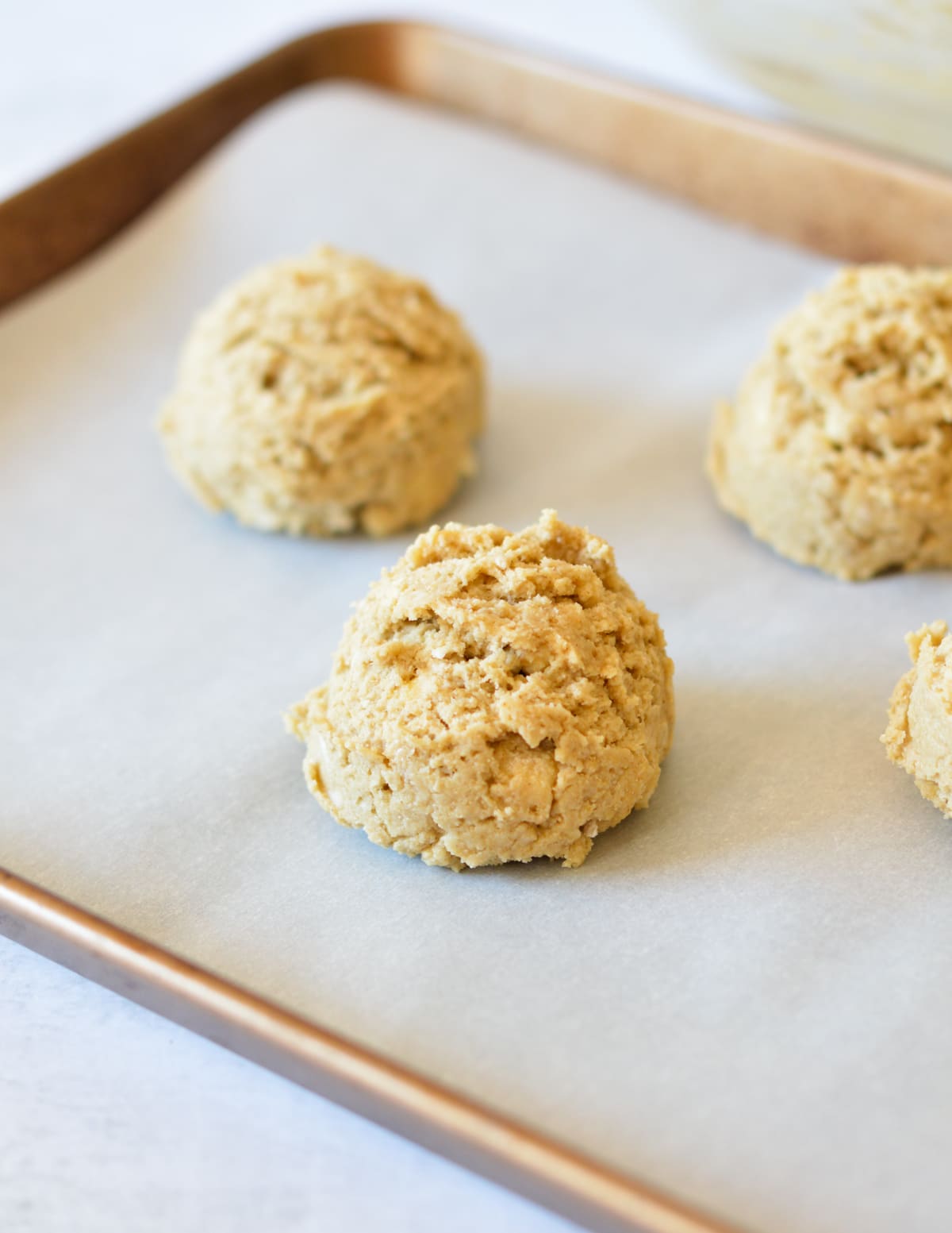 unbaked oat flour drop biscuits on a parchment lined sheet pan.