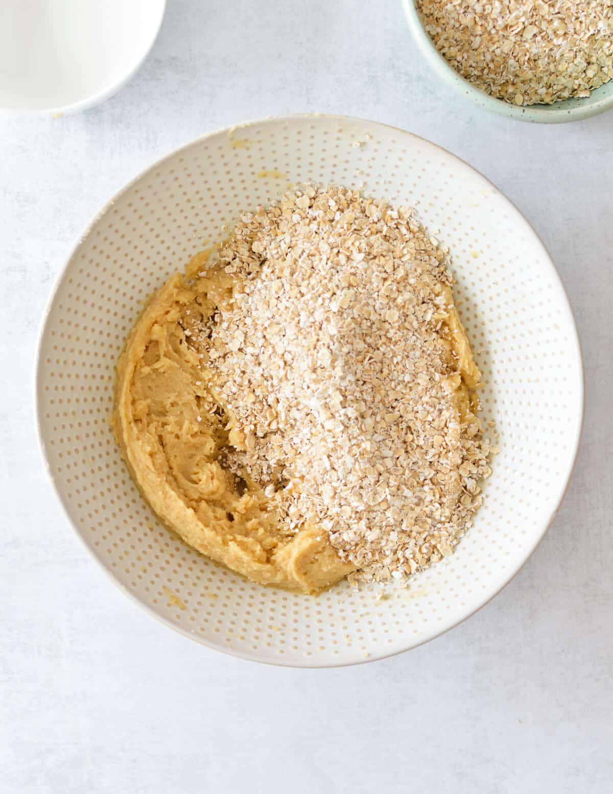 a bowl of creamed butter, sugar, and egg with oats on top.