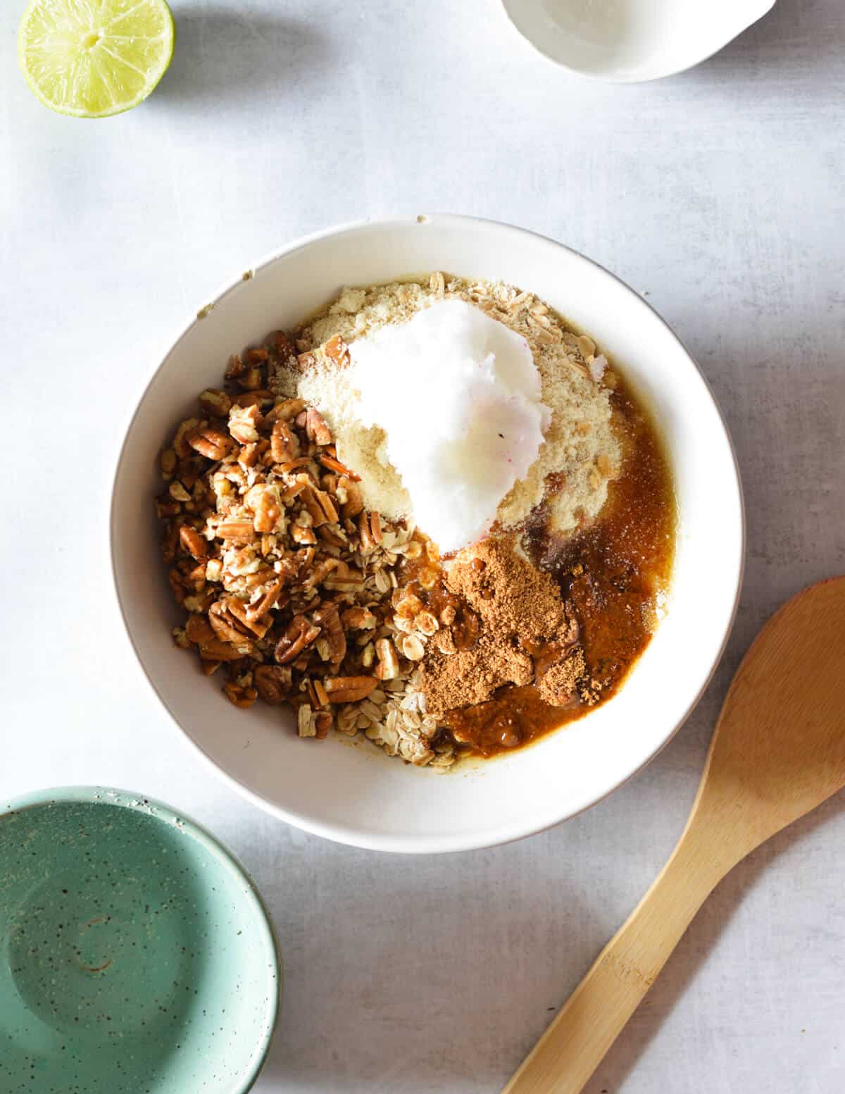 a bowl of coconut oil, almond flour, oats, coconut sugar, and maple syrup.