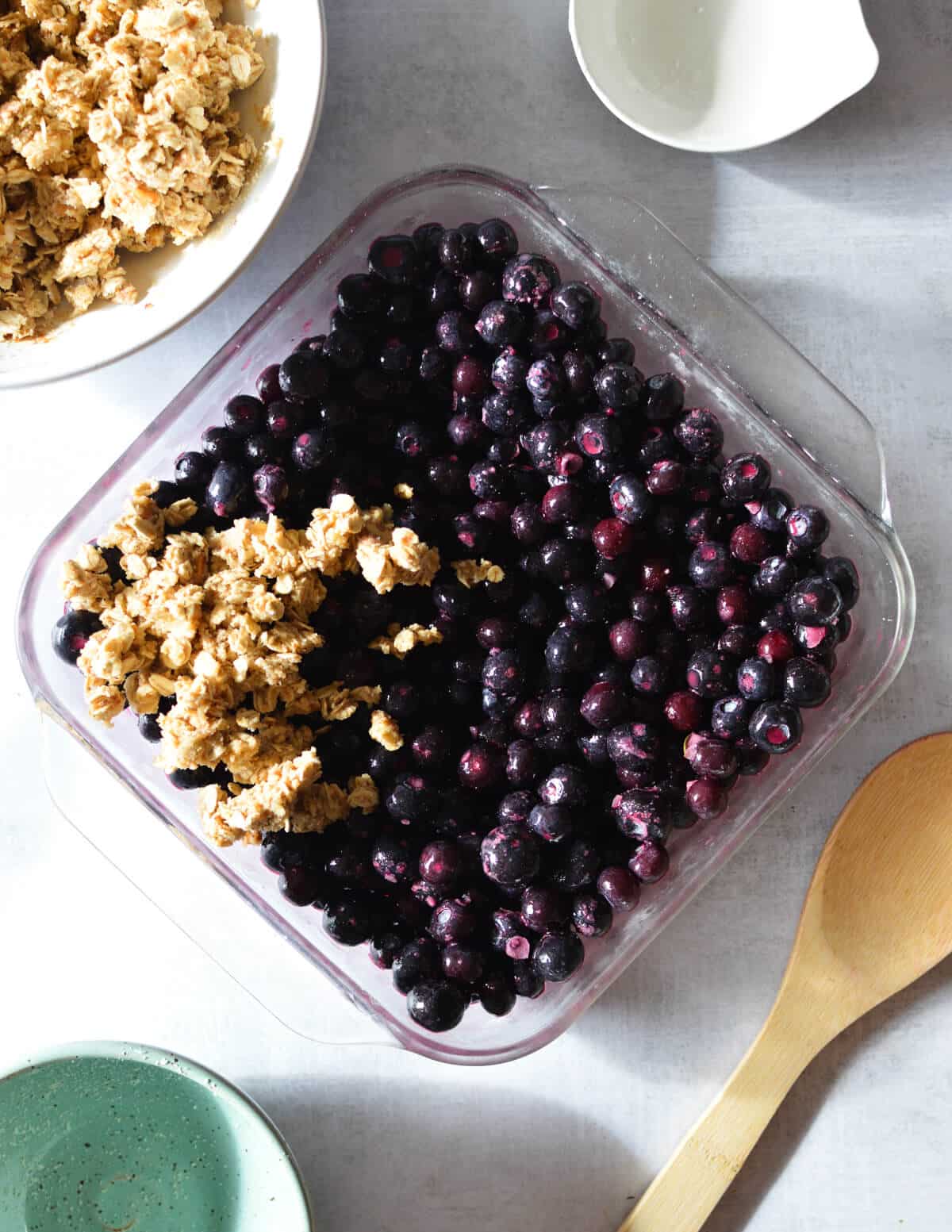 blueberries in baking dish with crumble in the corner.