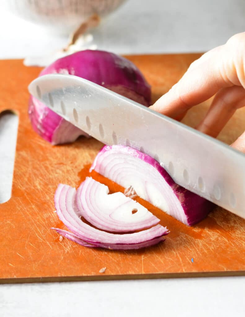 hand slicing the red onion thinly. 