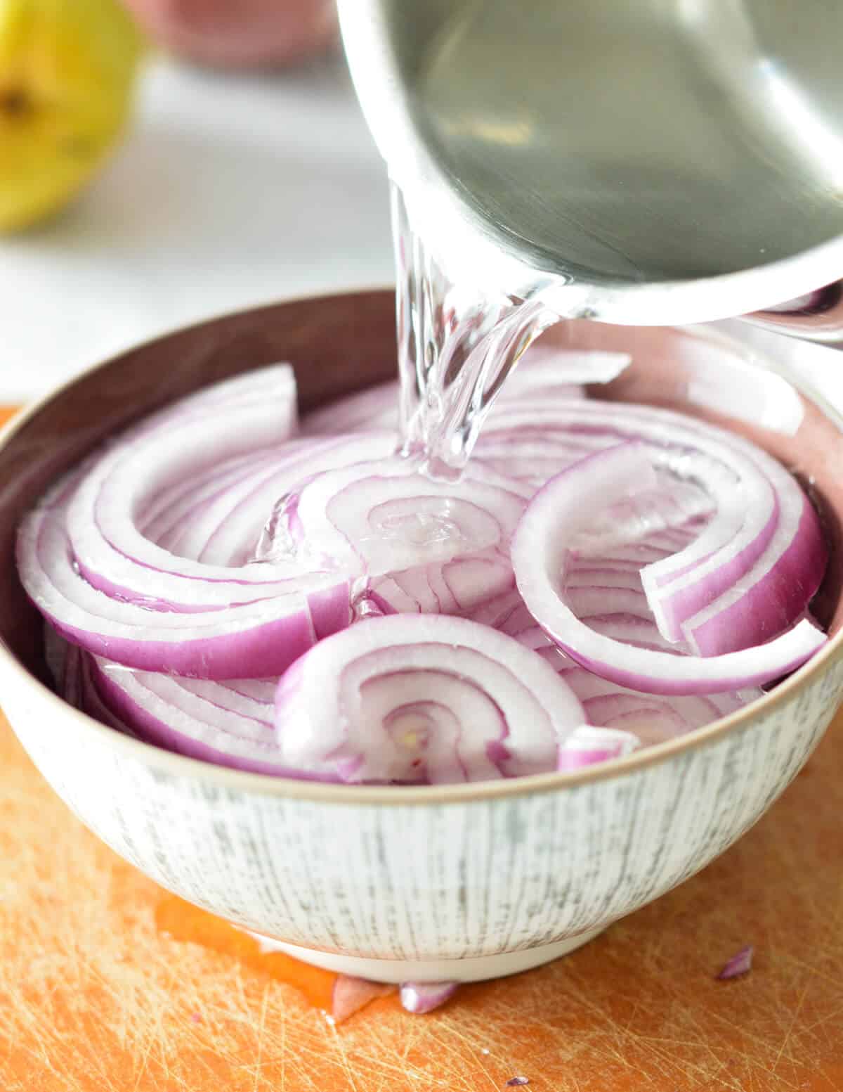 pouring hot water onto red onions.