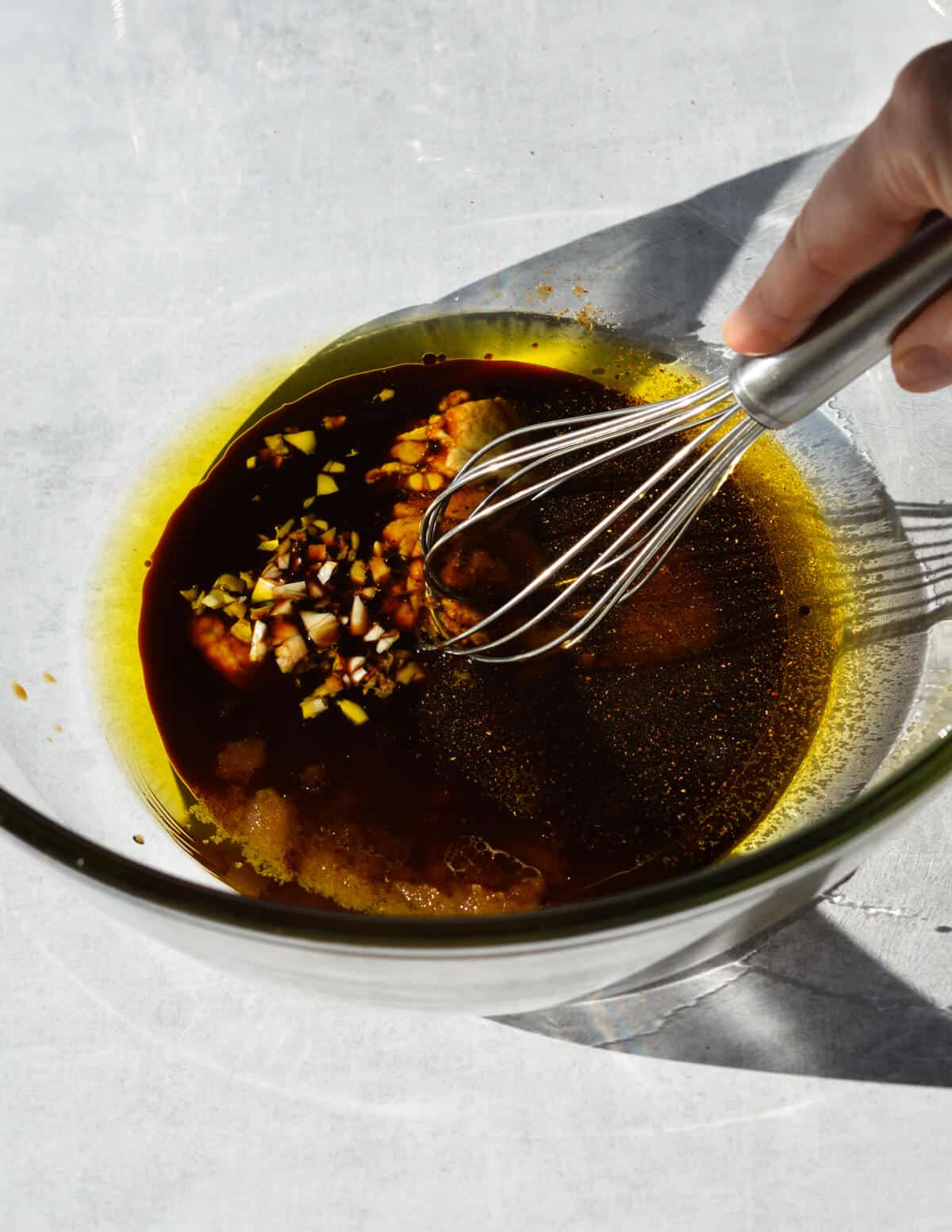 a bowl of oil, balsamic vinegar, brown sugar, dijon mustard, and garlic.