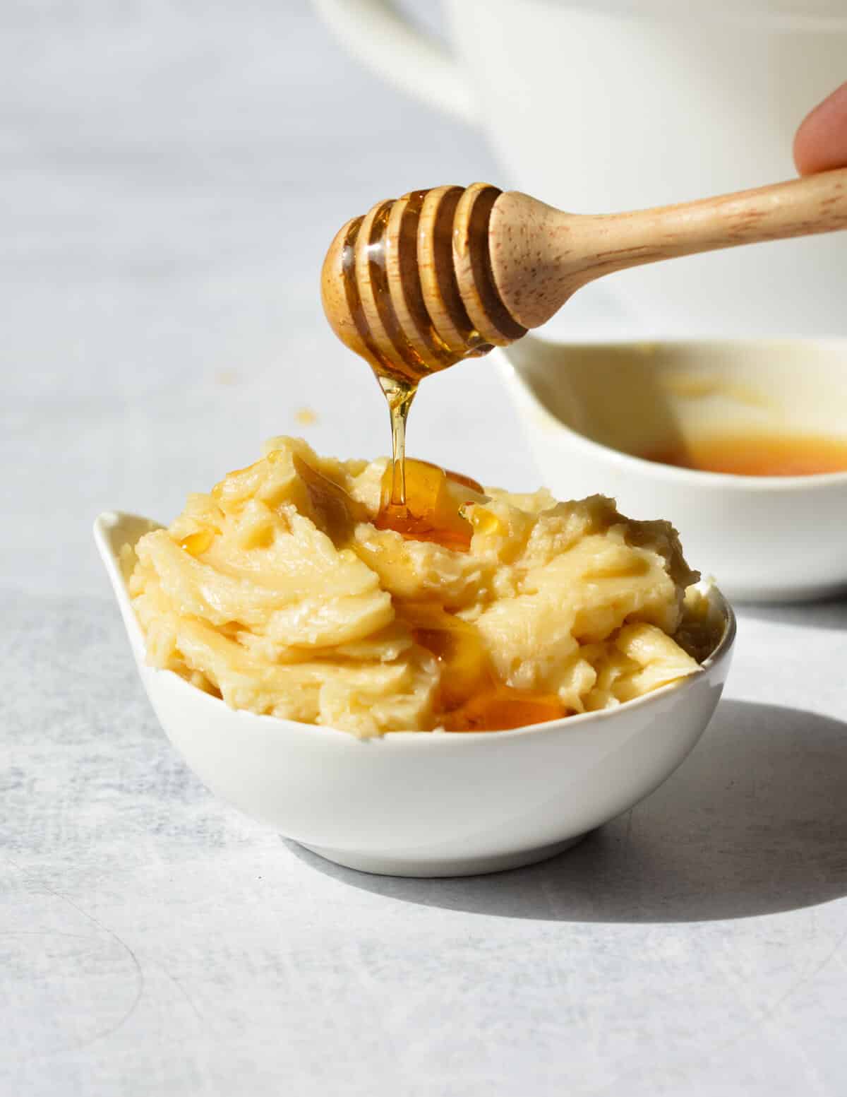 drizzling honey onto a bowl of honey butter