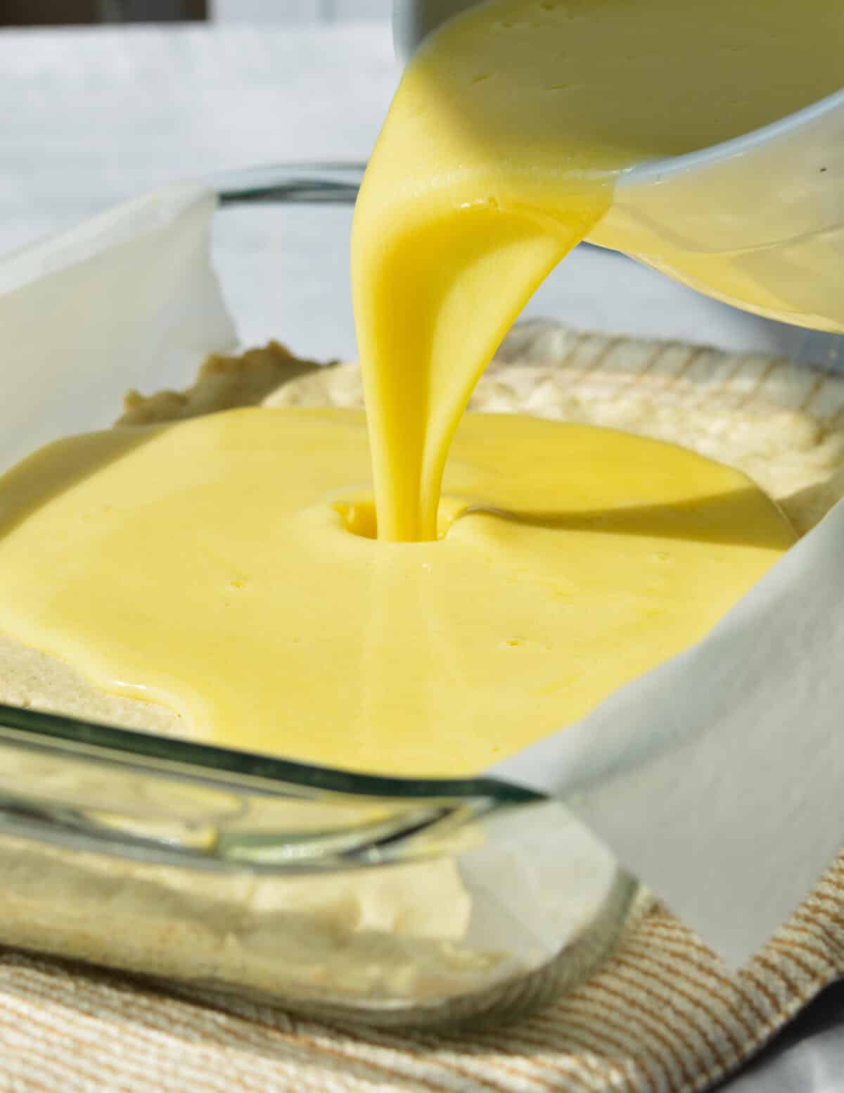 pouring key lime filling into a baked shortbread crust.