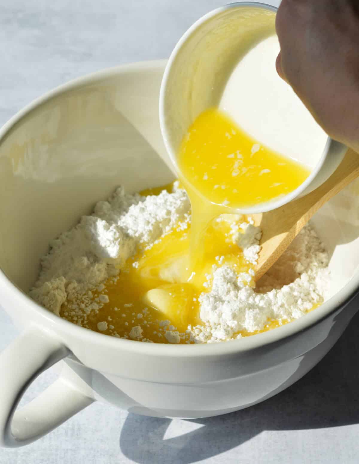 pouring butter into a bowl with flour and sugar.