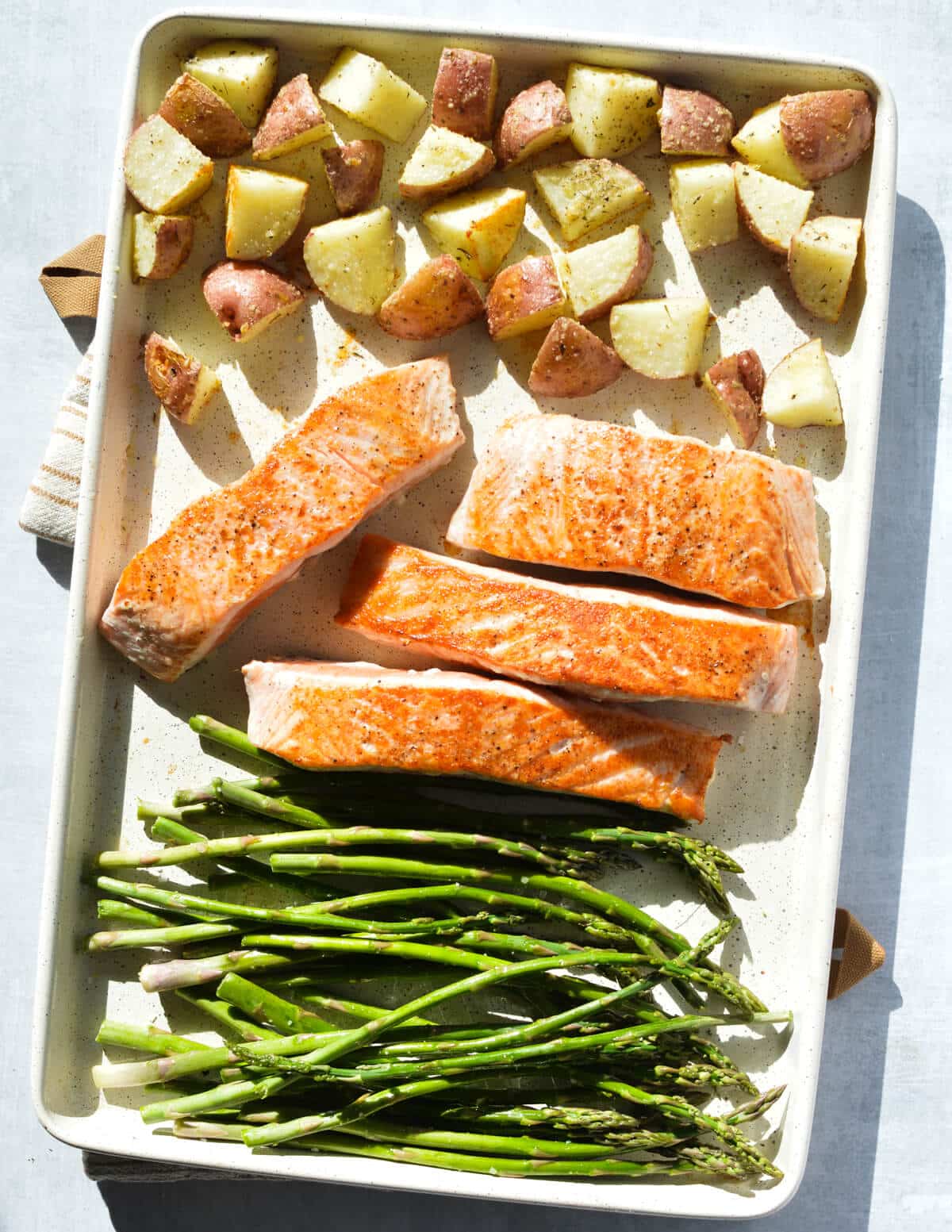 roasted potatoes, seared salmon fillets, and asparagus on a sheet pan.