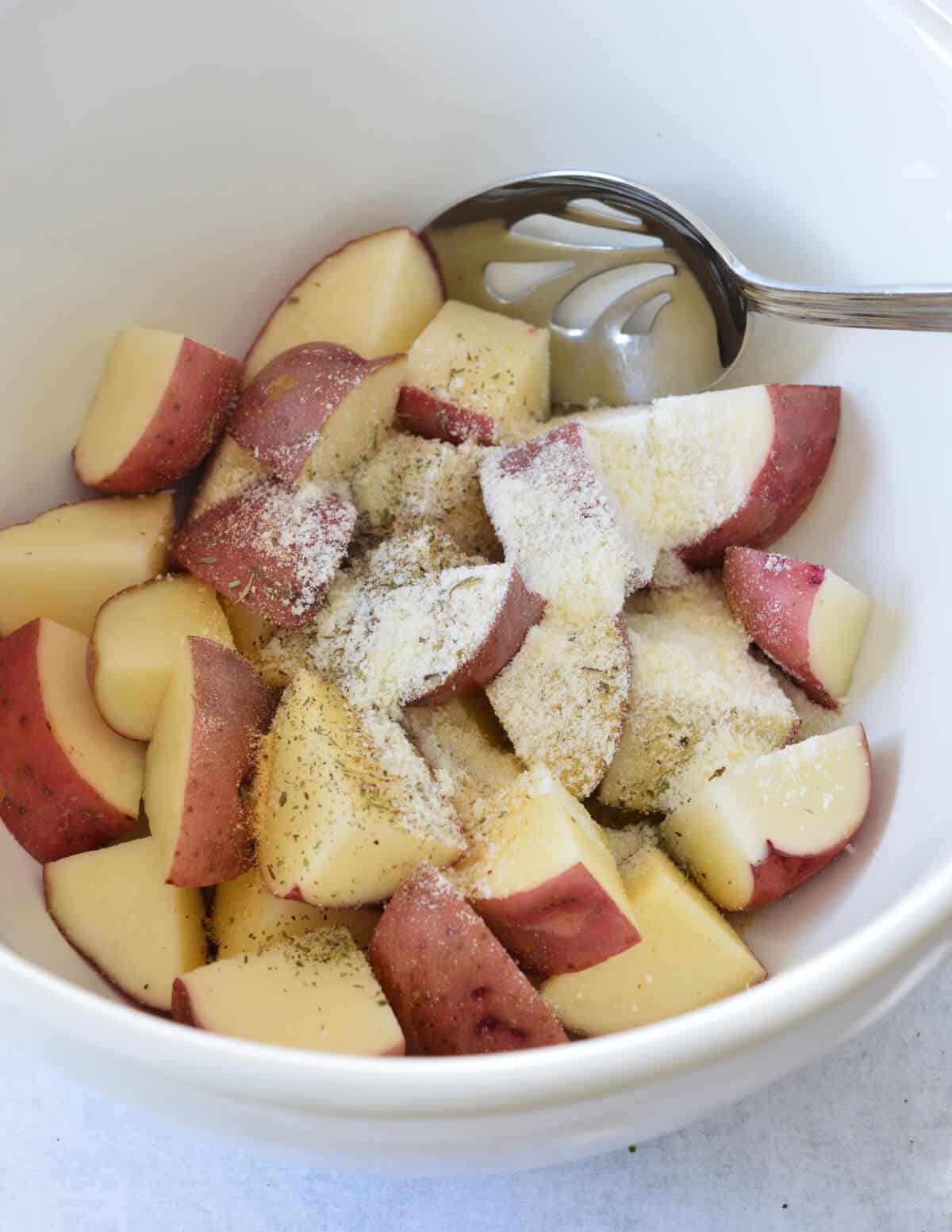 a bowl of cut red potatoes, parmesan, olive oil, and seasoning. 