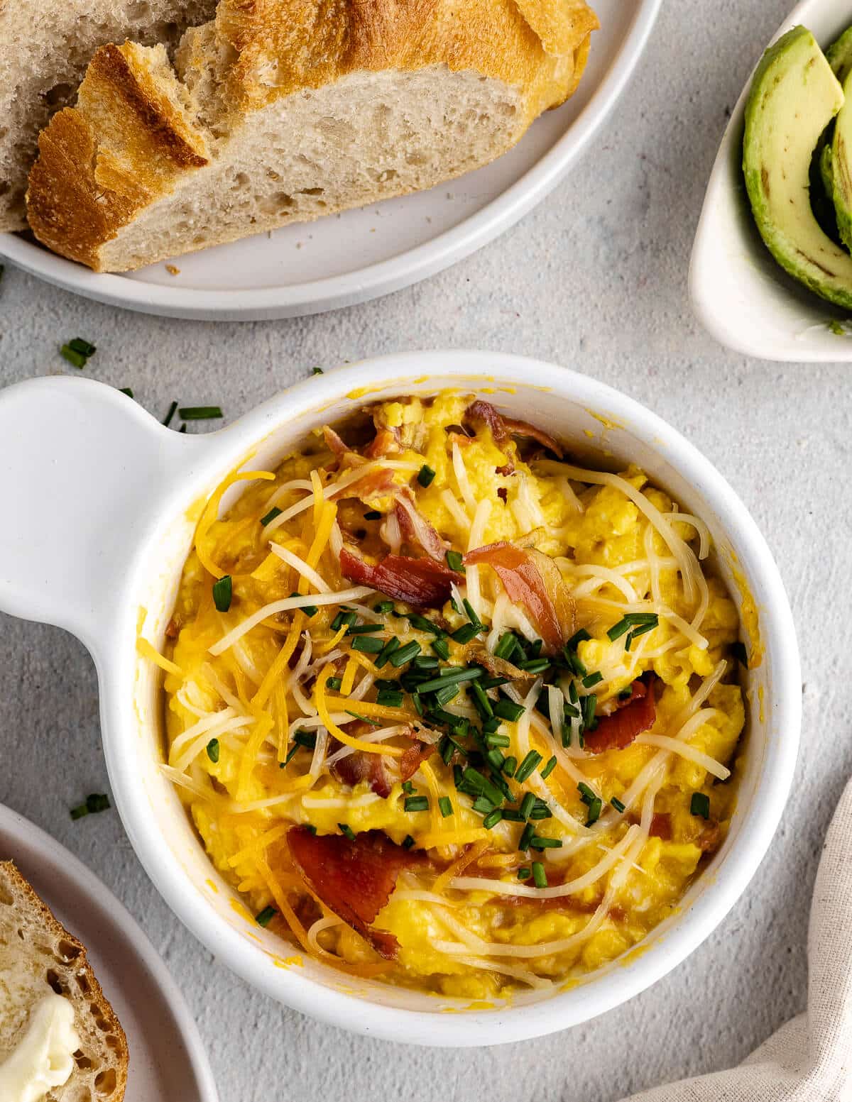 a bowl of cheesy scrambled eggs with shredded cheese and chives on top.