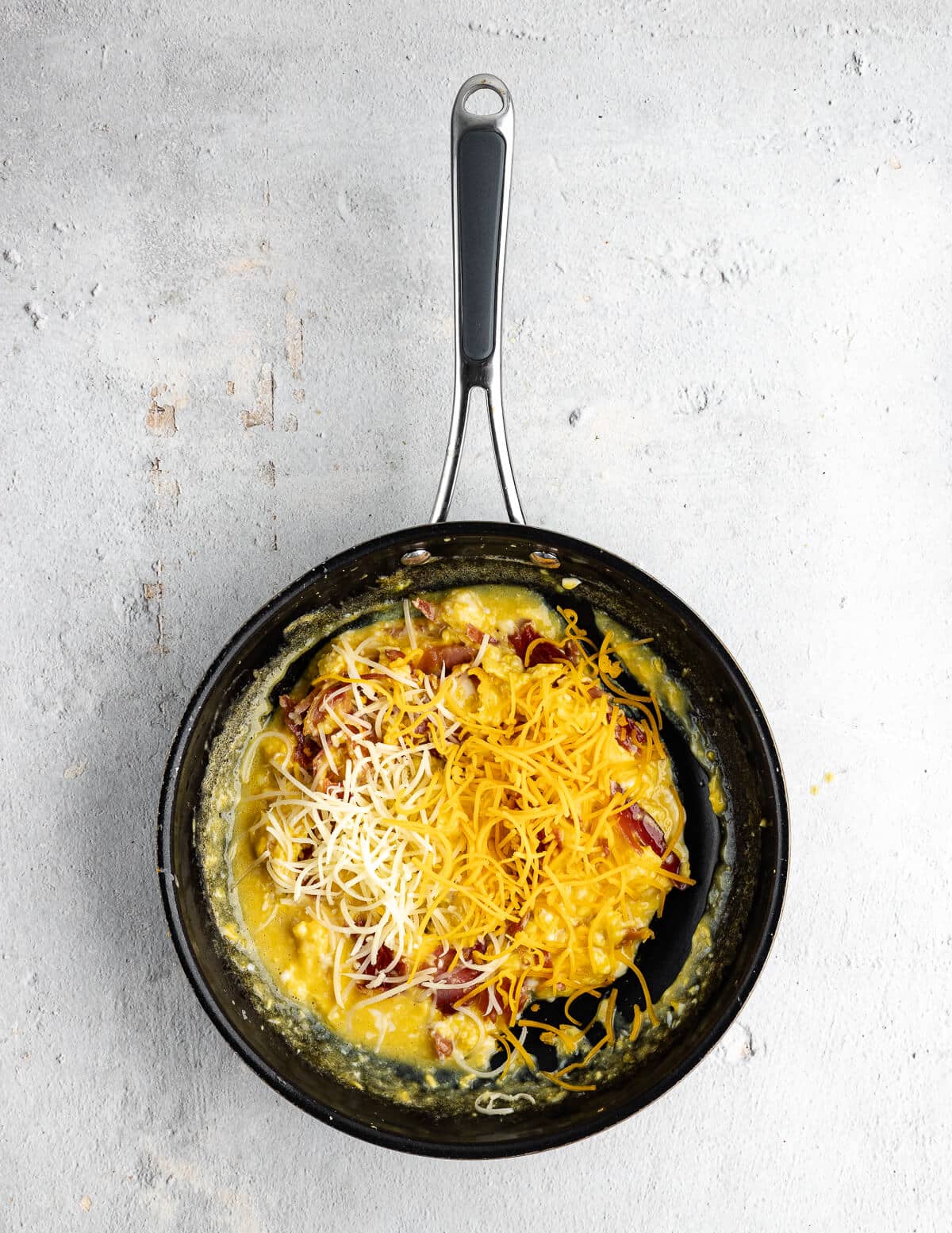 scrambled eggs in a skillet with shredded cheddar cheese on top.