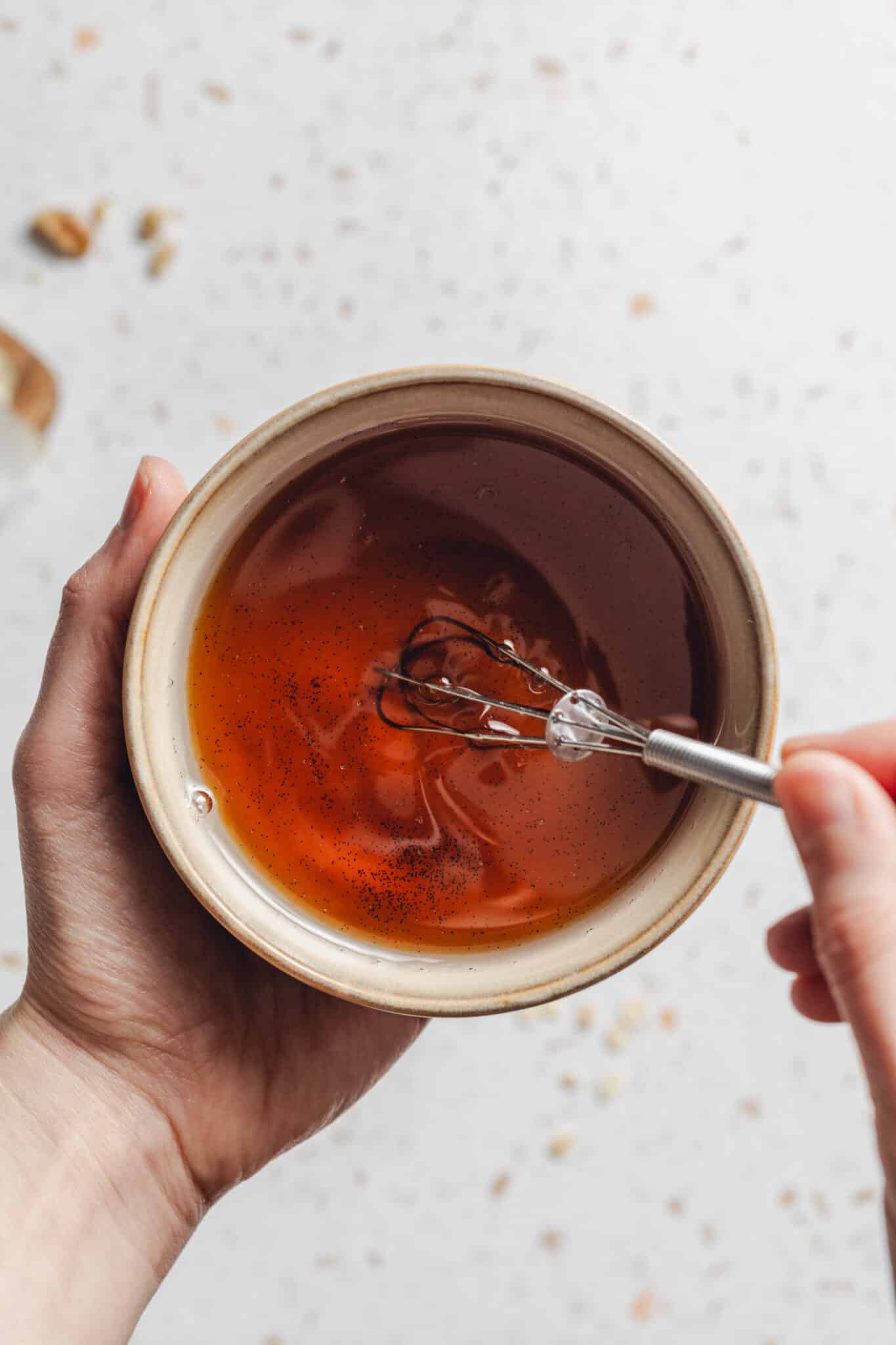 whisking a bowl of coconut oil, maple syrup and vanilla together.
