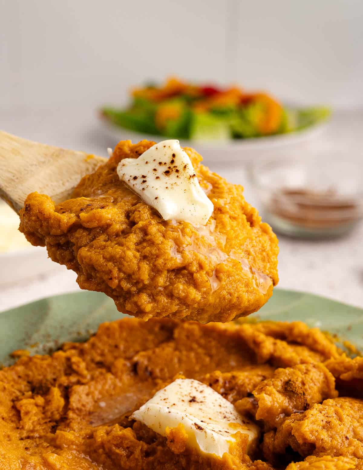 a spoonful of mashed sweet potatoes with butter and cinnamon on top.