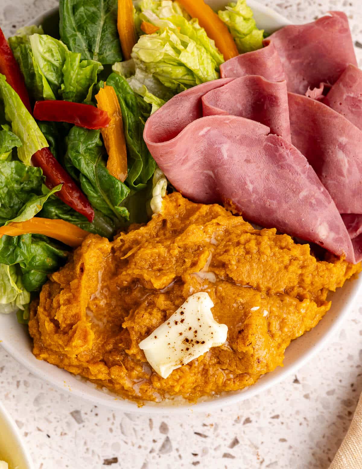 mashed sweet potatoes with sliced ham and salad.