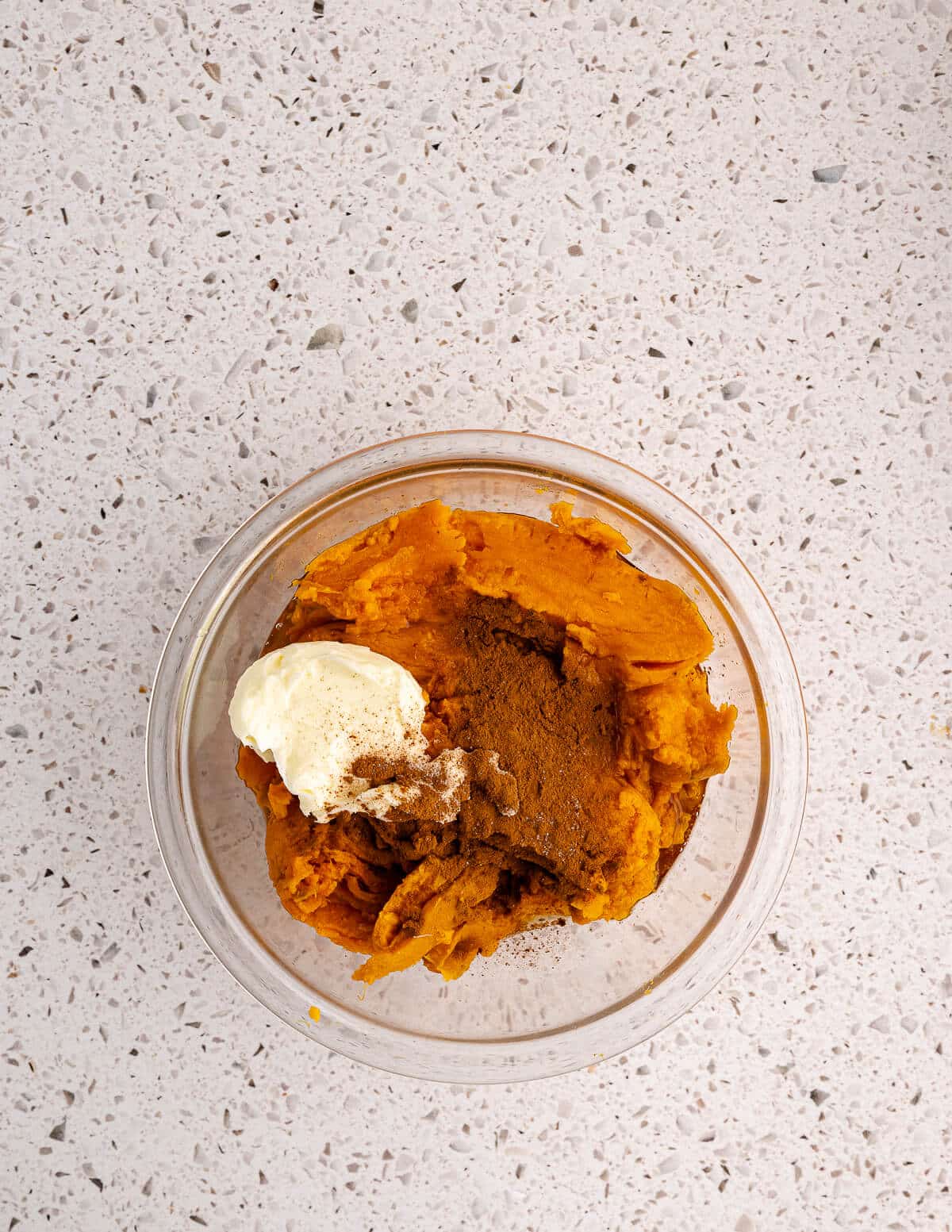 cooked sweet potatoes in a bowl with butter and cinnamon on top.