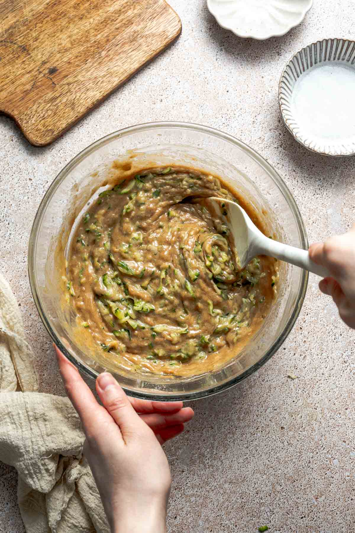 stirring gluten free zucchini bread batter in a bowl. 