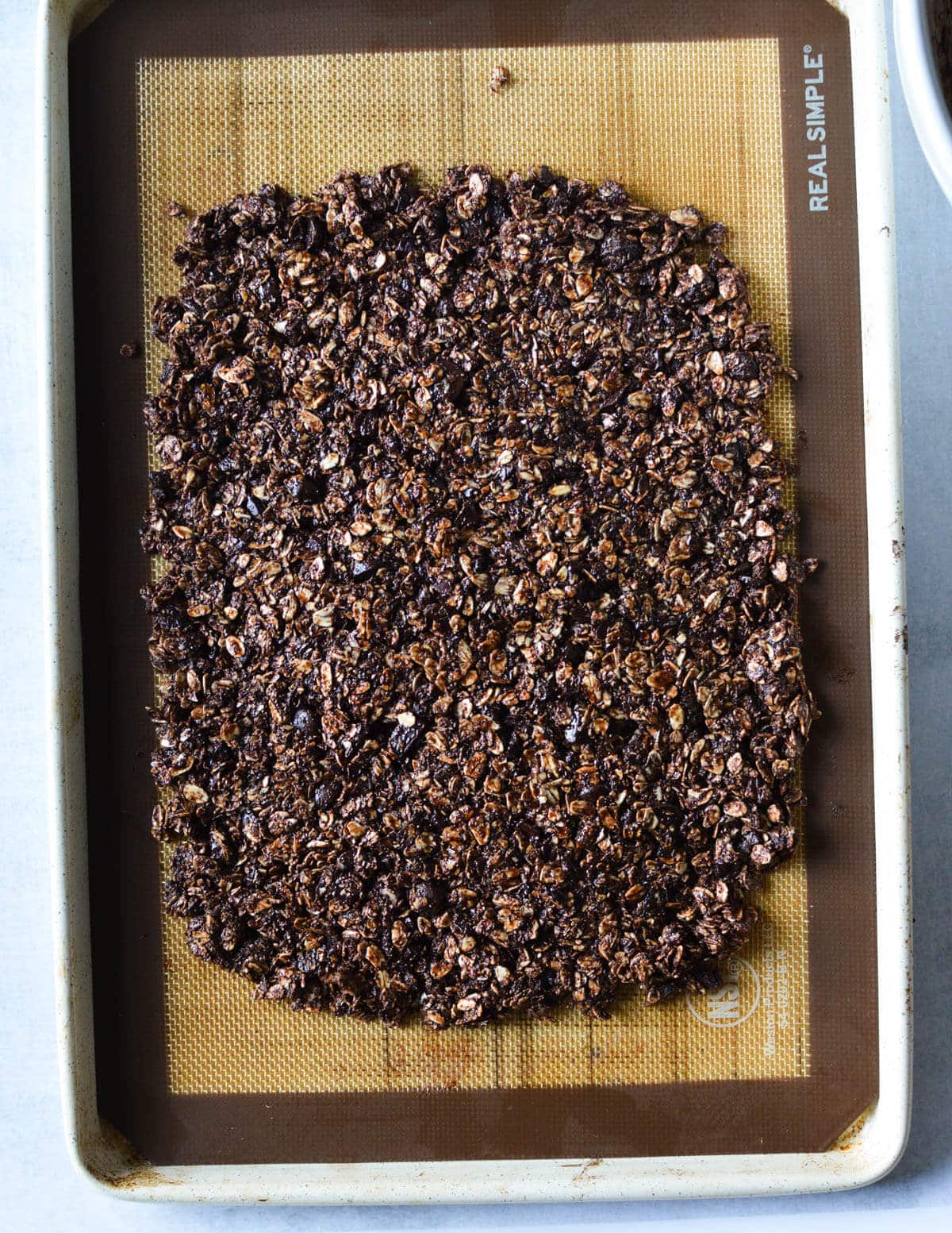 large rectangle of unbaked chocolate granola on a sheet pan.